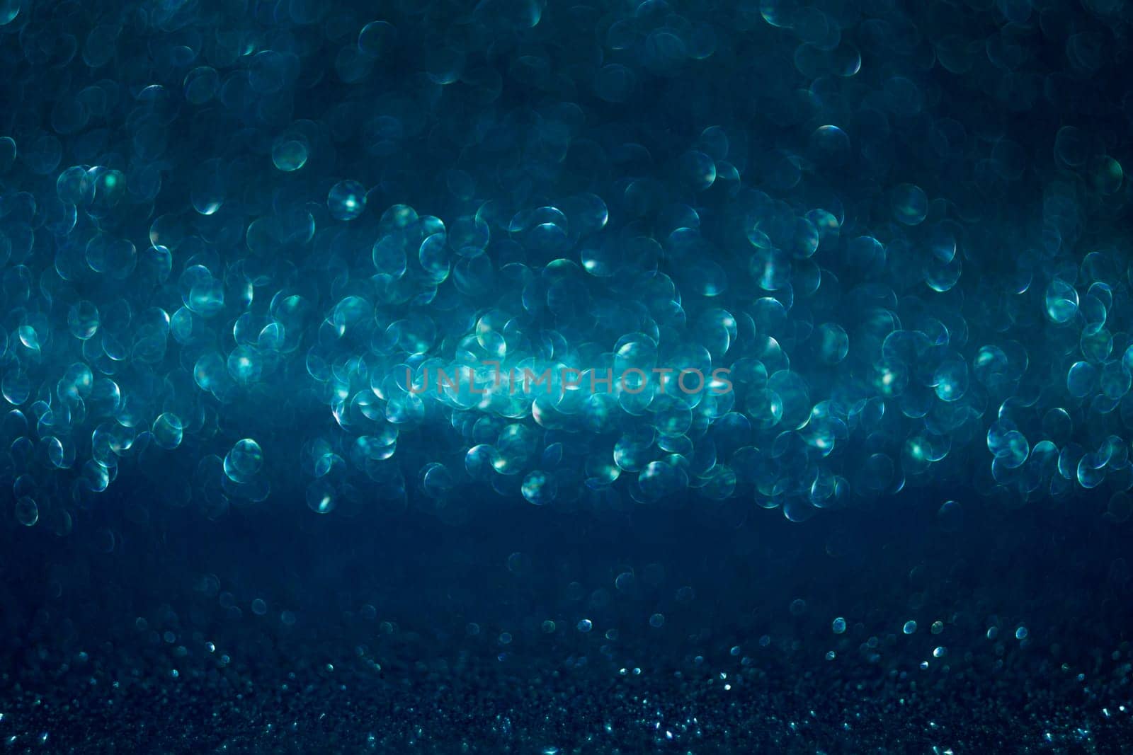 The image is a blue background with many small, round, and blurry dots. The dots are scattered throughout the image, creating a sense of movement and depth