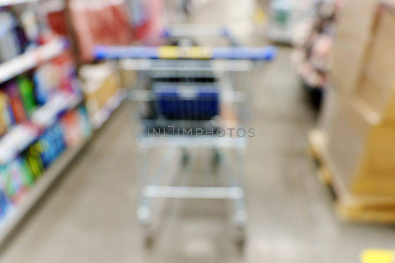 Blurry shot of a shopping cart in a busy store aisle, showcasing the hustle and bustle of shopping activities.