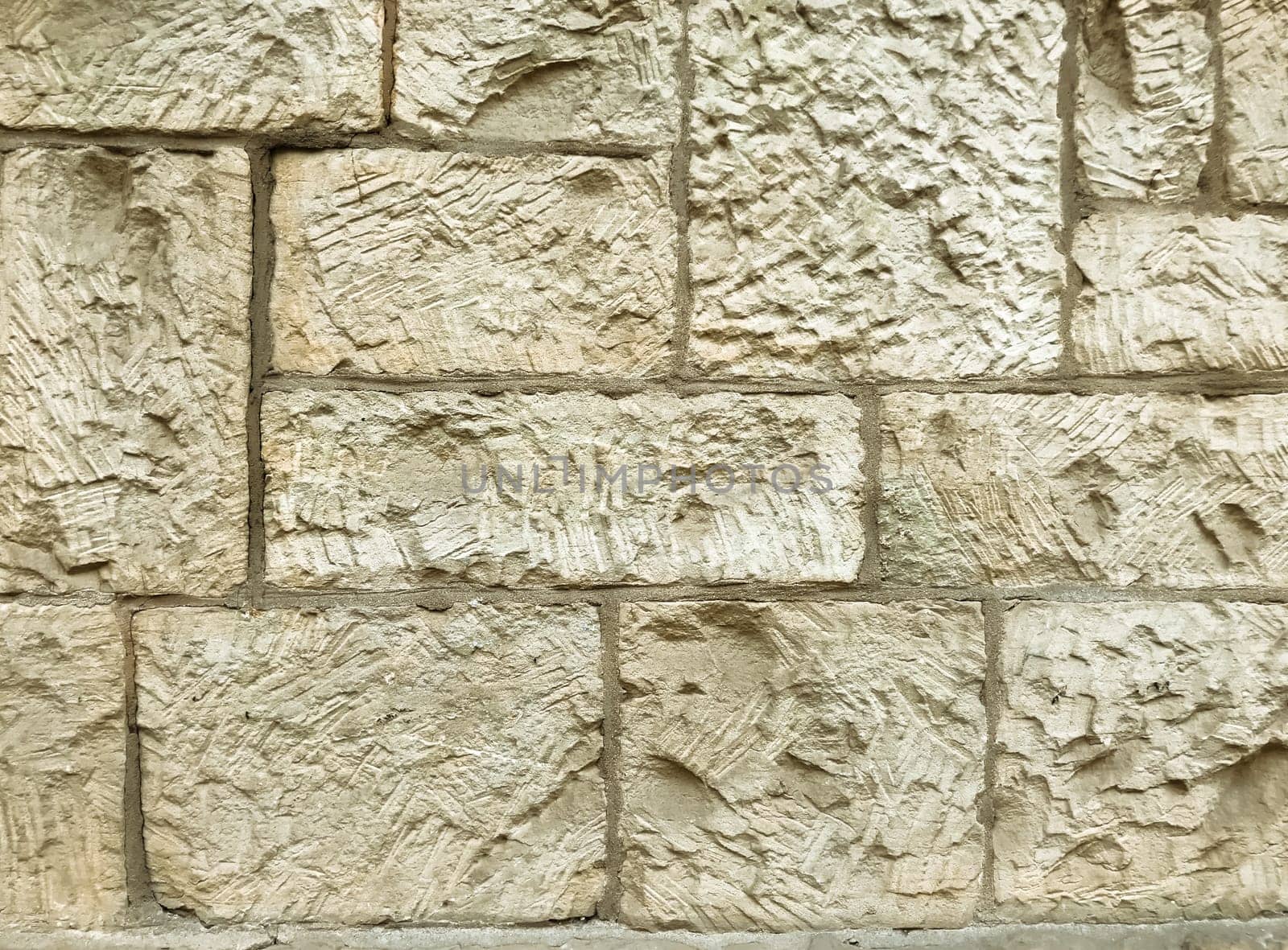 A wall made of stone with a rough texture. The wall is white and has a stone-like appearance