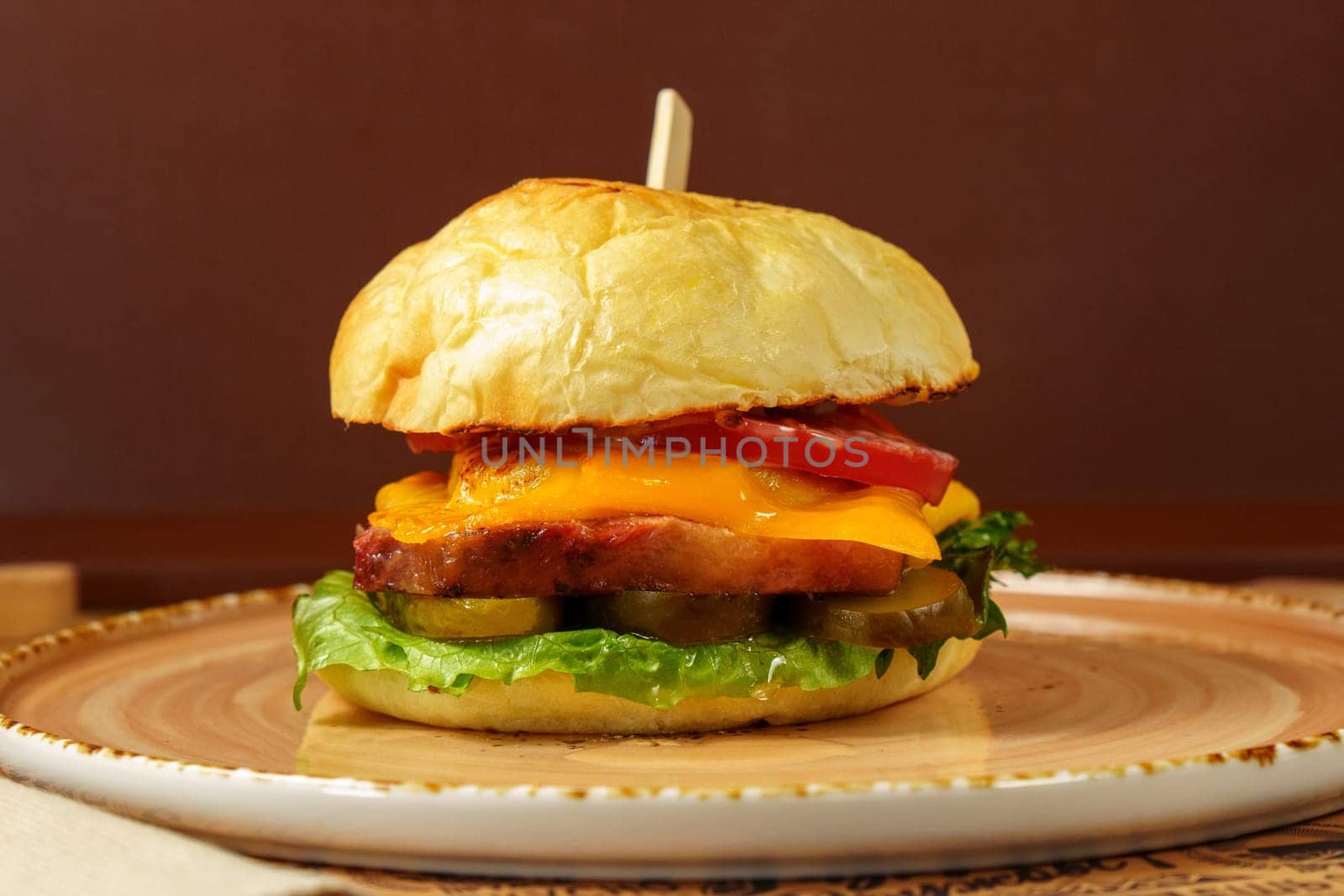 Cheeseburger topped with fresh lettuce and tomato on a sesame seed bun, ready to be enjoyed.