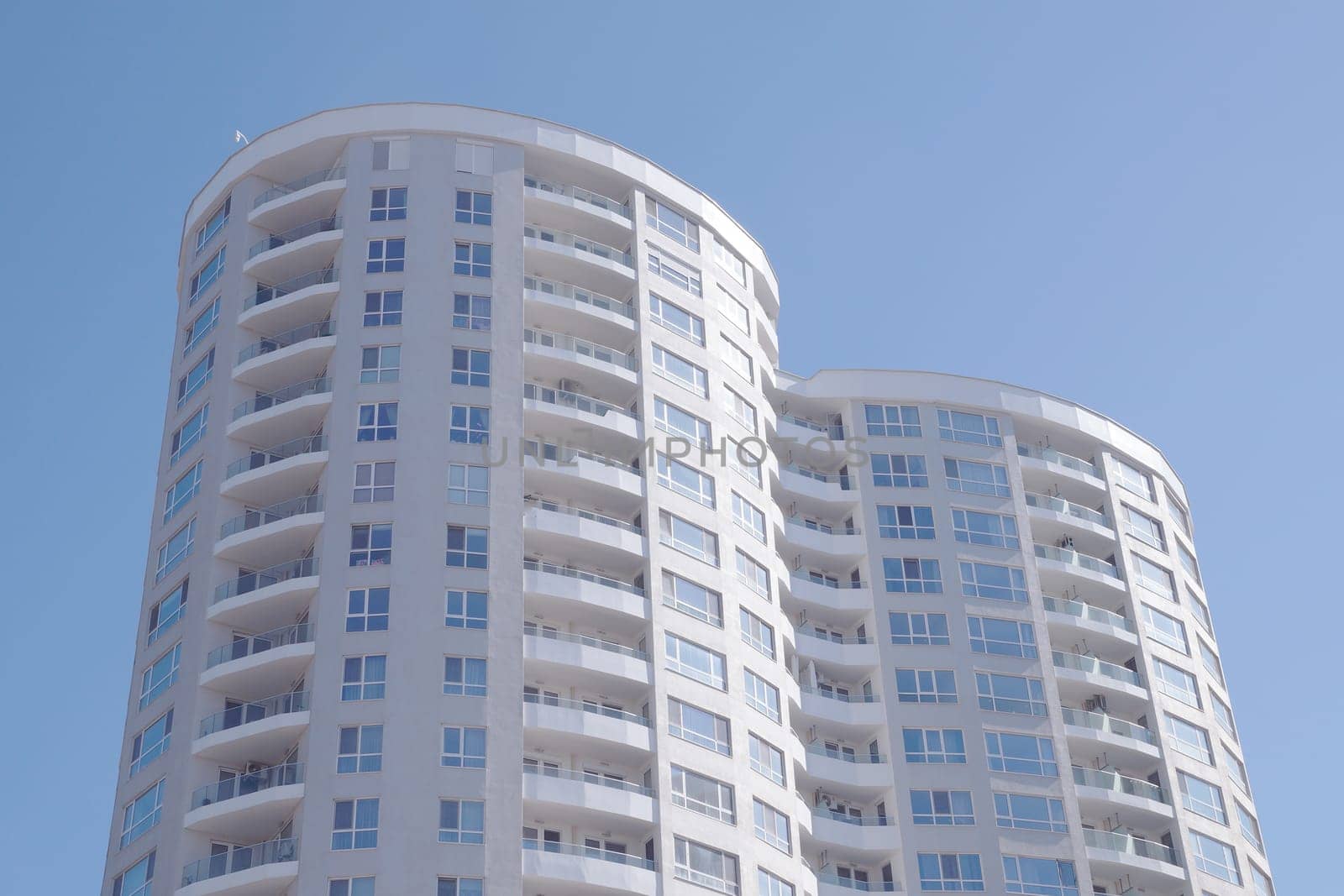 Burgas, Bulgaria - March 23, 2024: Modern high-rise residential building with curved balconies against a blue sky