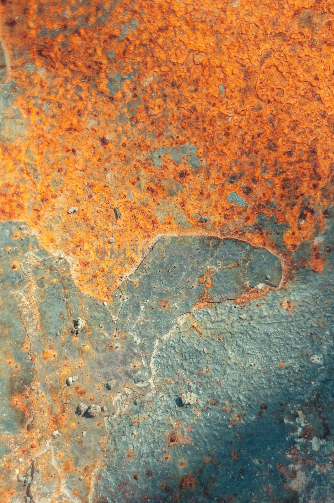 The image is of a rusty surface with a blue and orange color scheme. The surface appears to be old and worn, with a lot of rust and dirt. Scene is somewhat bleak and desolate