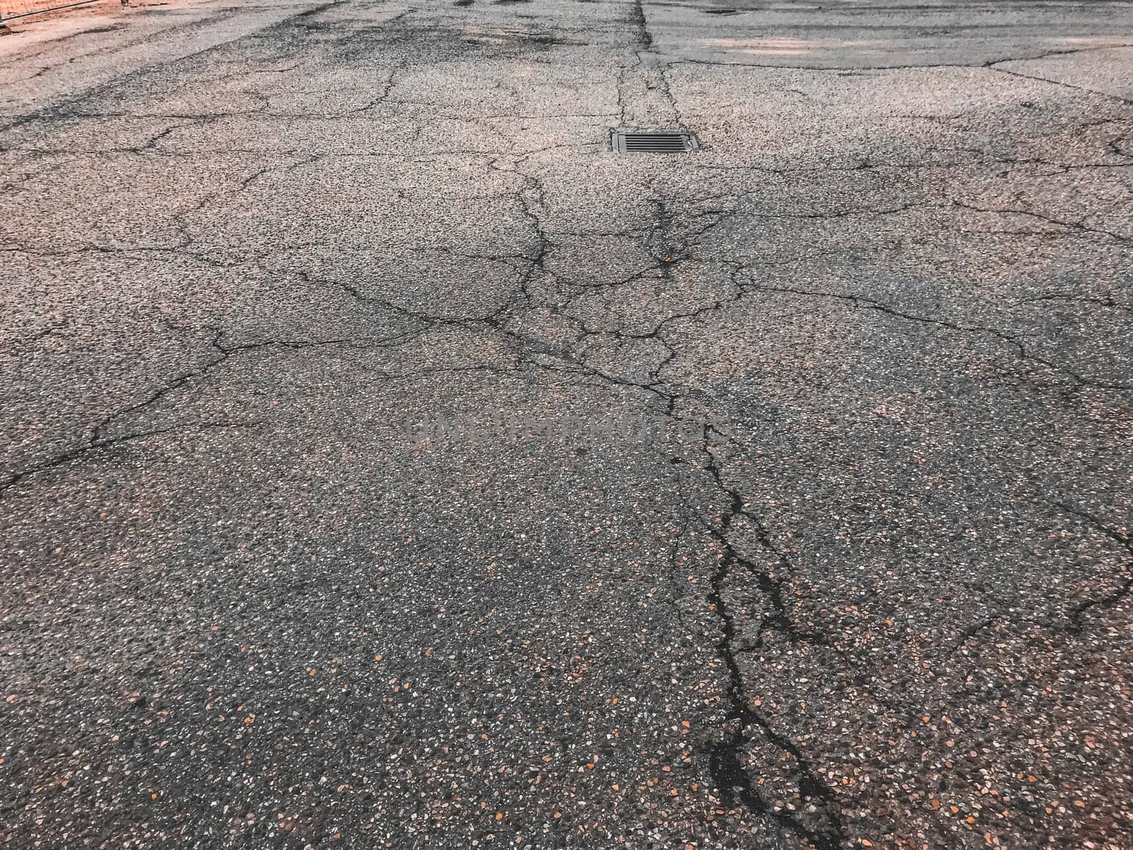 A cracked and broken road with a hole in the middle. The road is in a state of disrepair and is not safe for driving
