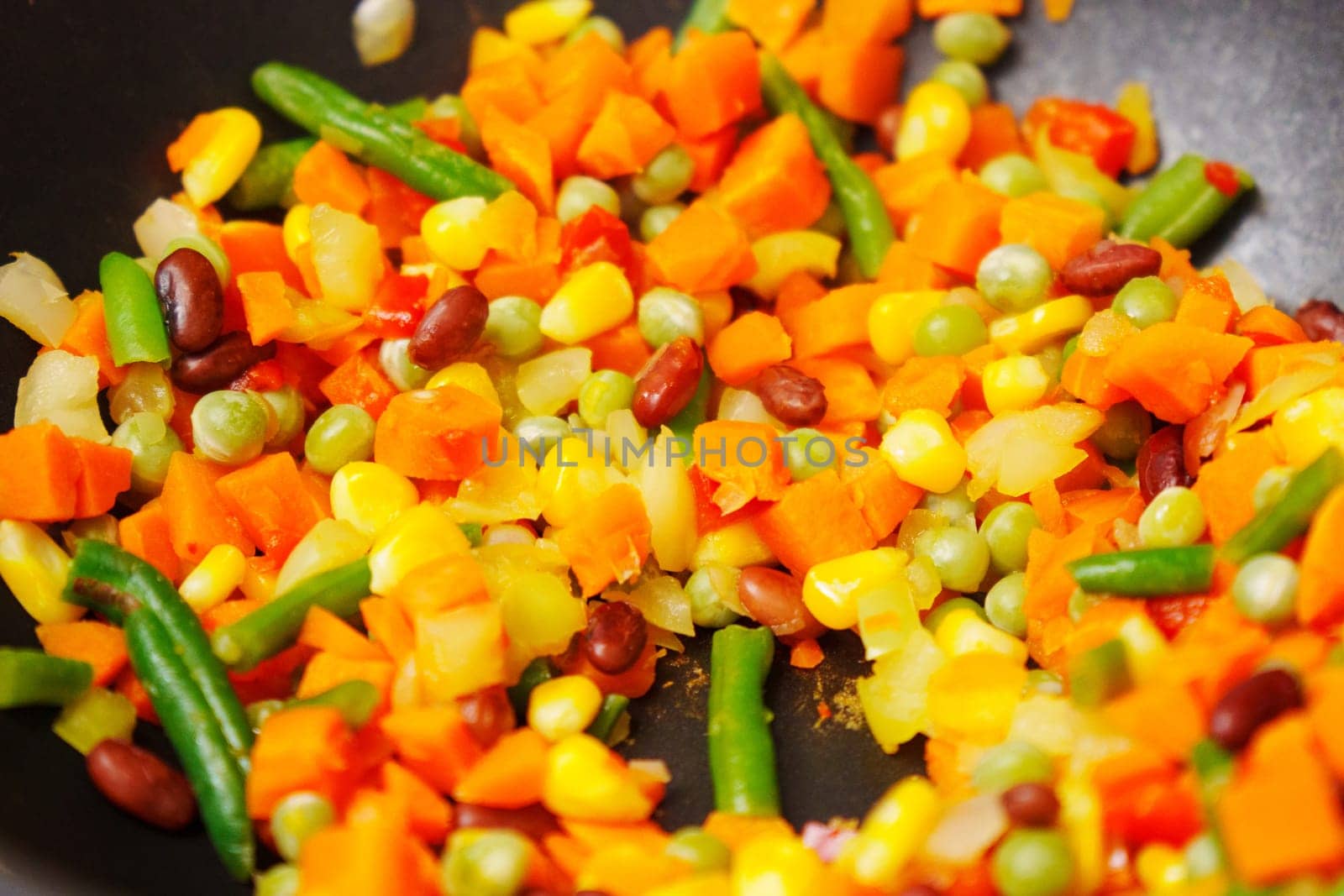 Colorful chopped vegetables is being stirred using a wooden spoon. The vegetables sizzle and release aromatic scents as they cook. by darksoul72