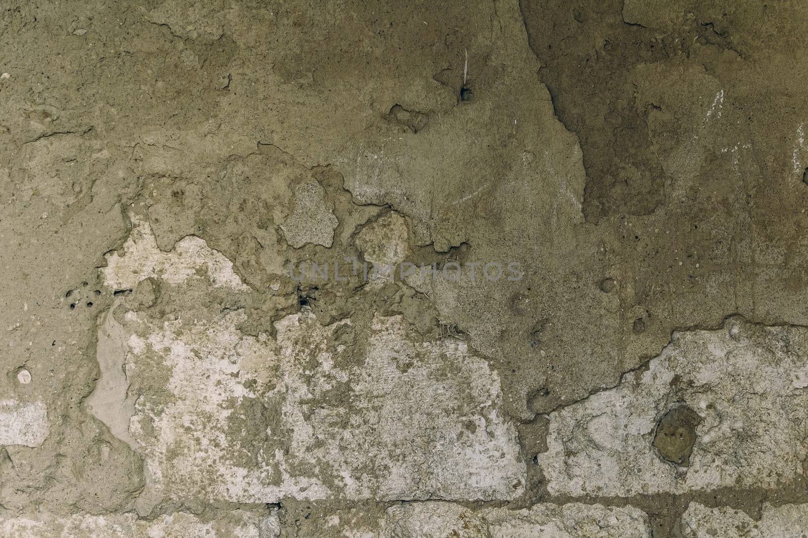 A wall with a rough, textured surface. The wall appears to be made of concrete and has a somewhat dirty, worn appearance