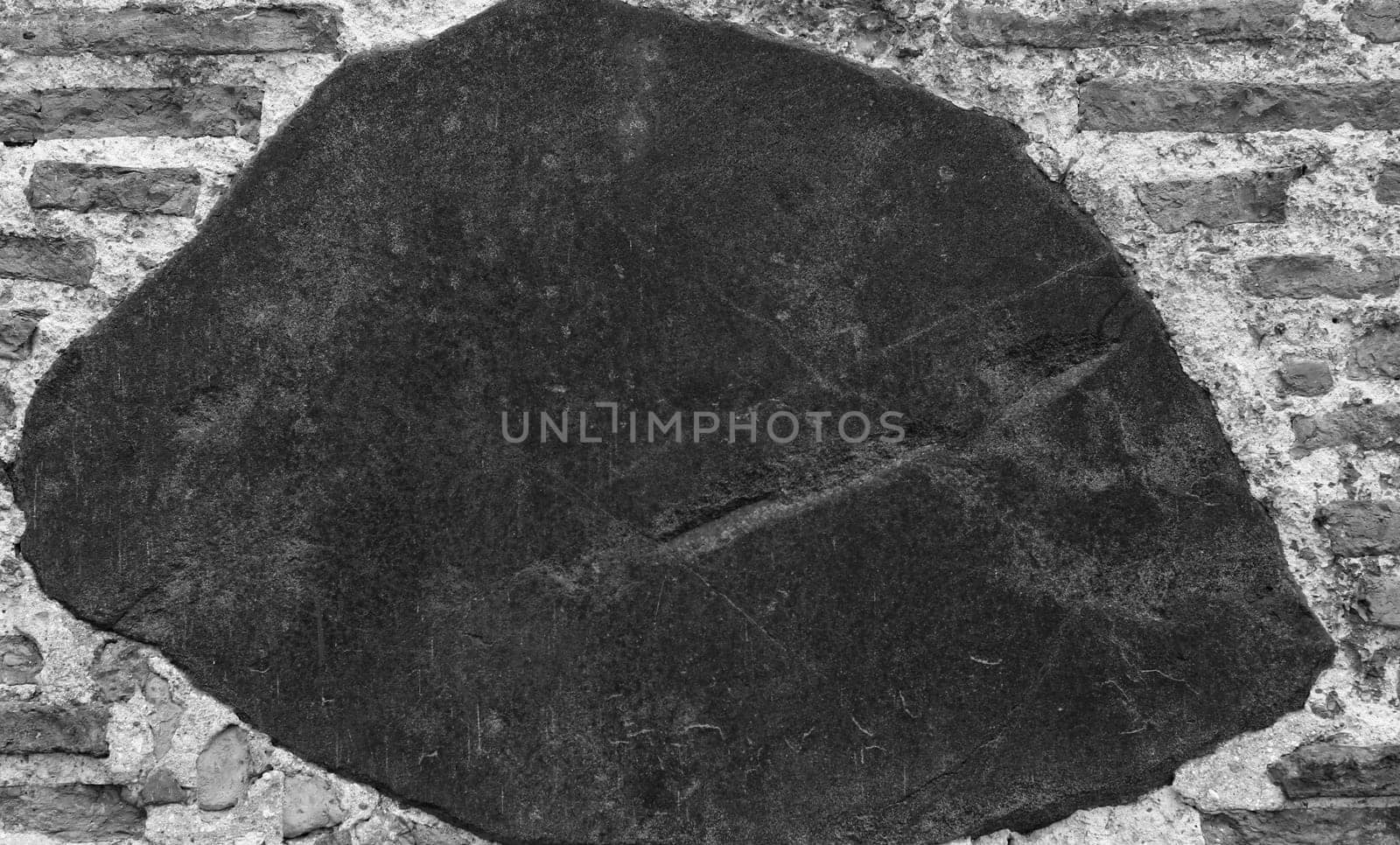 Black and white photo of a stone wall. The texture of the old ancient medieval antique stone