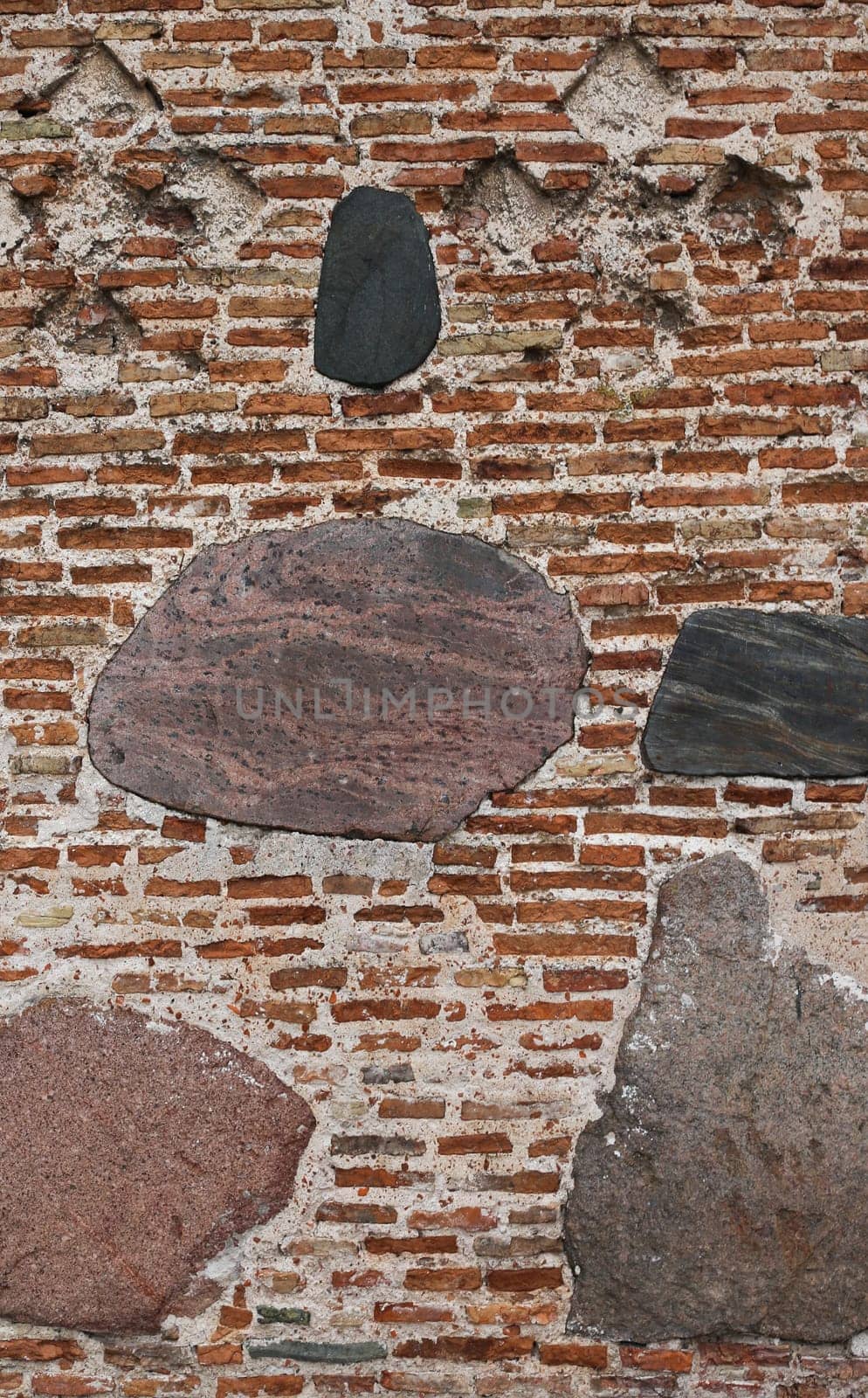 The texture of the old ancient medieval antique stone hard peeling cracked brick wall