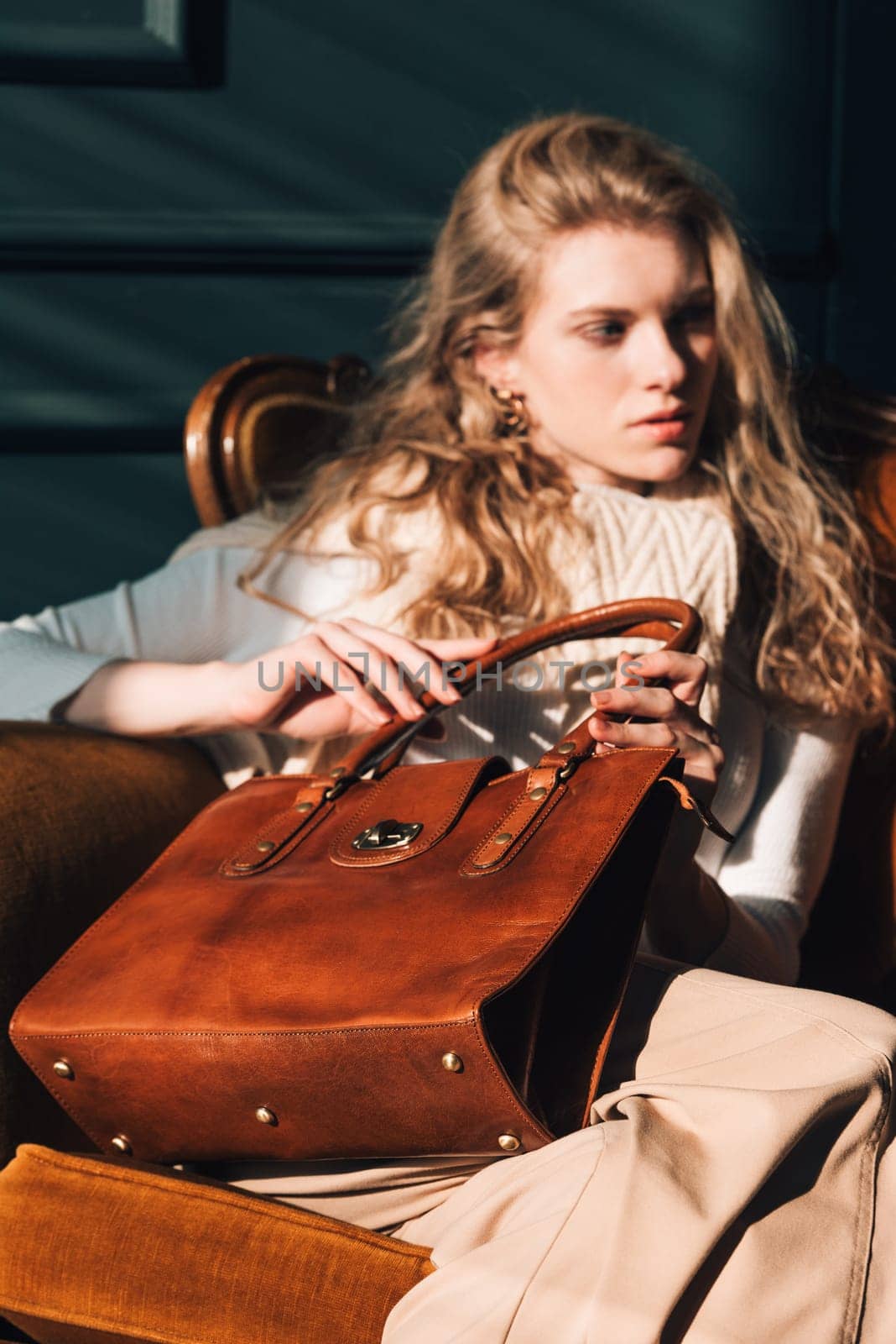 beautiful curly blond hair woman posing with a small shopper brown bag in a vintage chair by Ashtray25