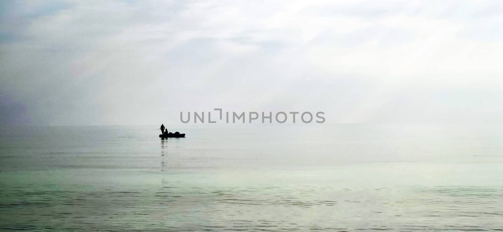 Shot of a man on a small catamaran boat by the horizon, which is hard to detect because of the fog and humidity. Outdoors by pazemin