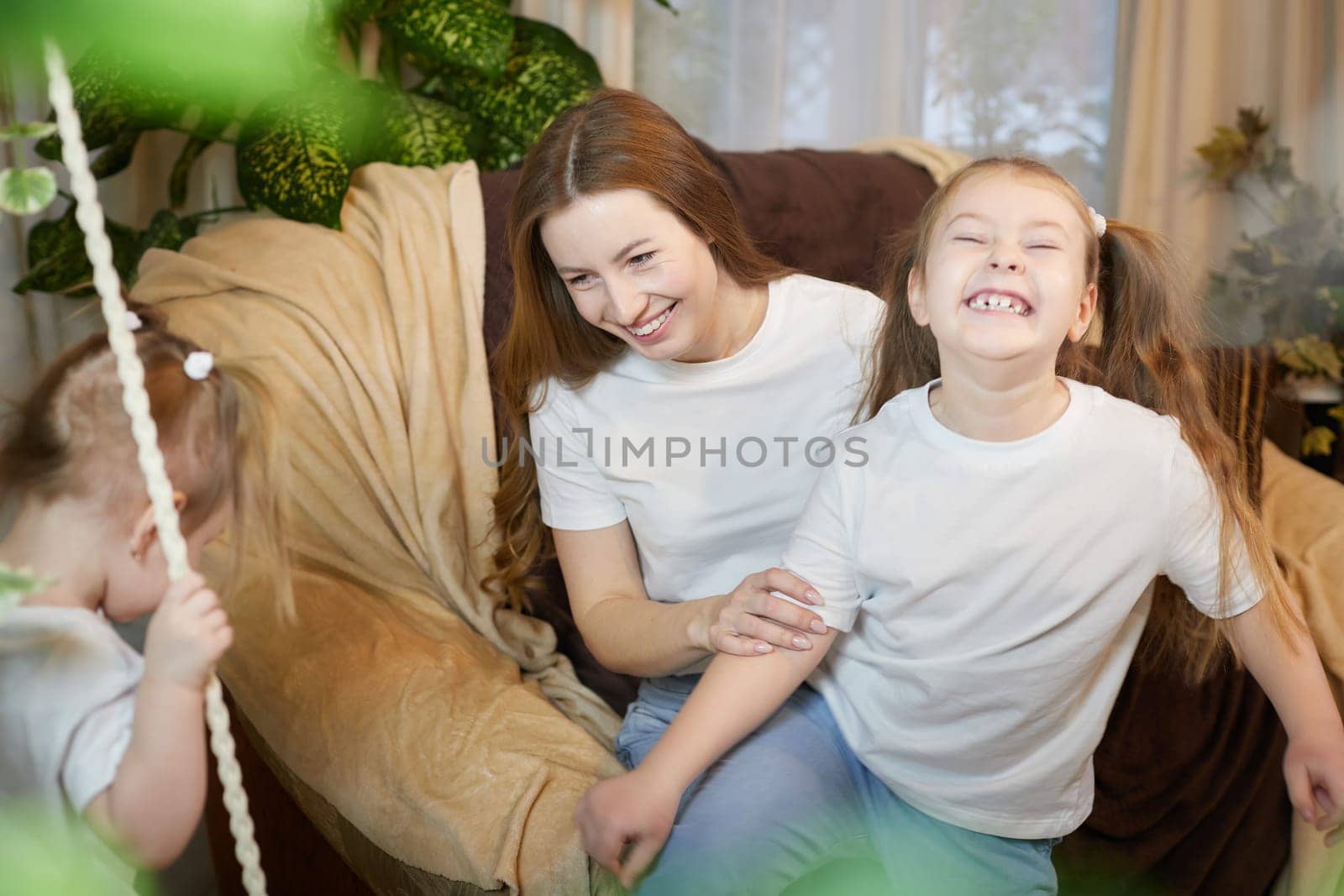 Happy family young mother babysitter relax having fun with cute little children daughters in living room at home
