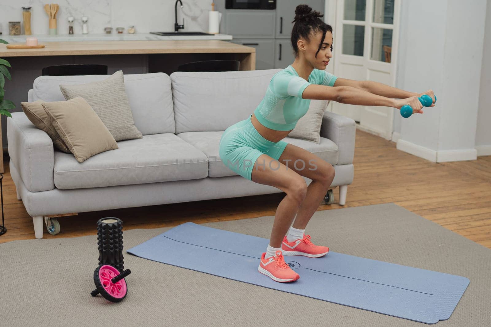 Training to become the best. Beautiful young woman in sports clothing exercising at home.