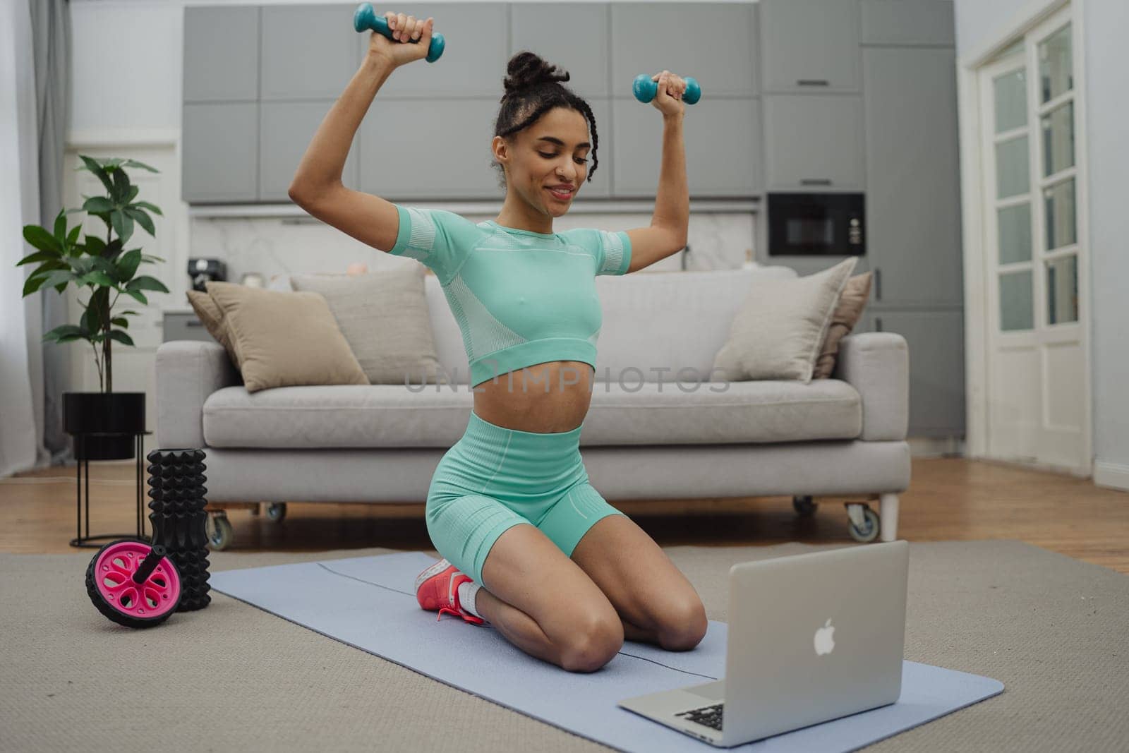 Training to become the best. Beautiful young woman in sports clothing exercising at home.