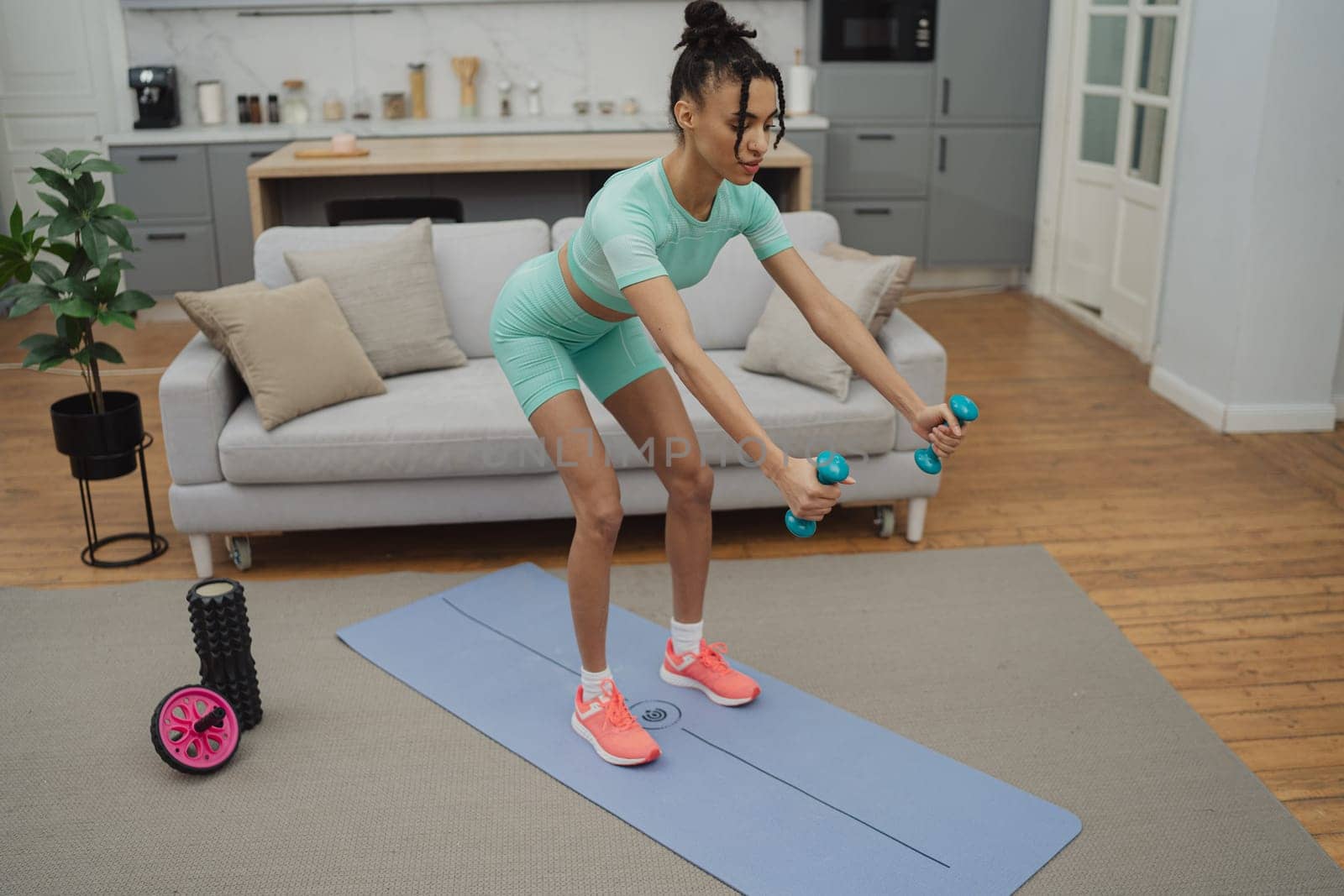 Training to become the best. Beautiful young woman in sports clothing exercising at home.