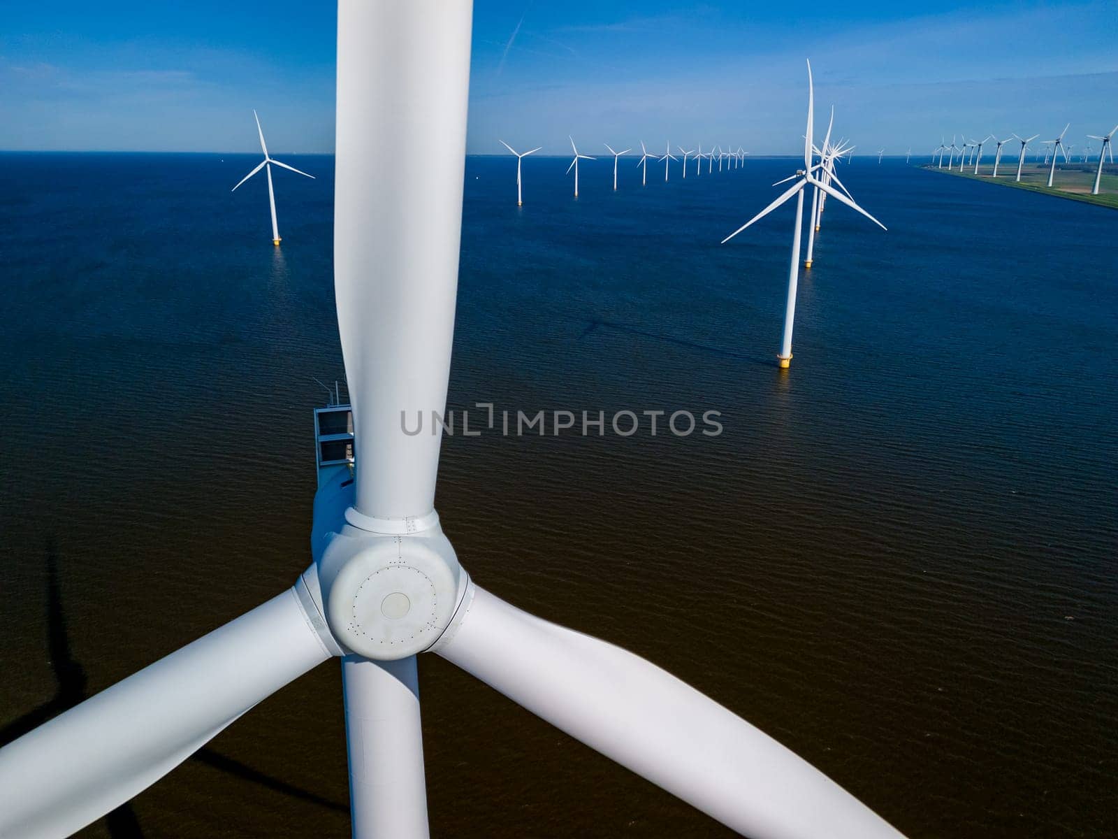 Serene wind farm in the ocean off the coast of Flevoland, Netherlands, with rows of majestic windmill turbines gracefully catching the spring breeze. windmill turbines green energy in the ocean