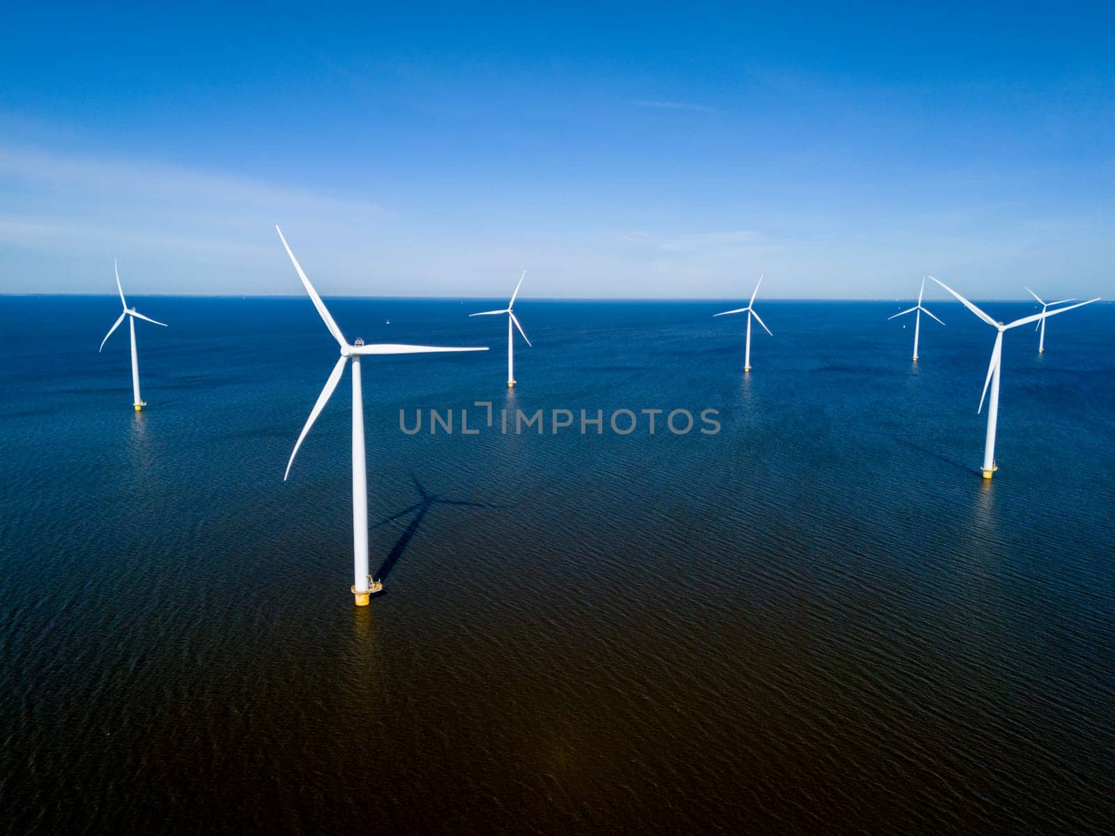 A group of wind turbines stand tall in the ocean, harnessing the power of the wind to generate renewable energy in the Netherlands Flevoland during the vibrant season of Spring.