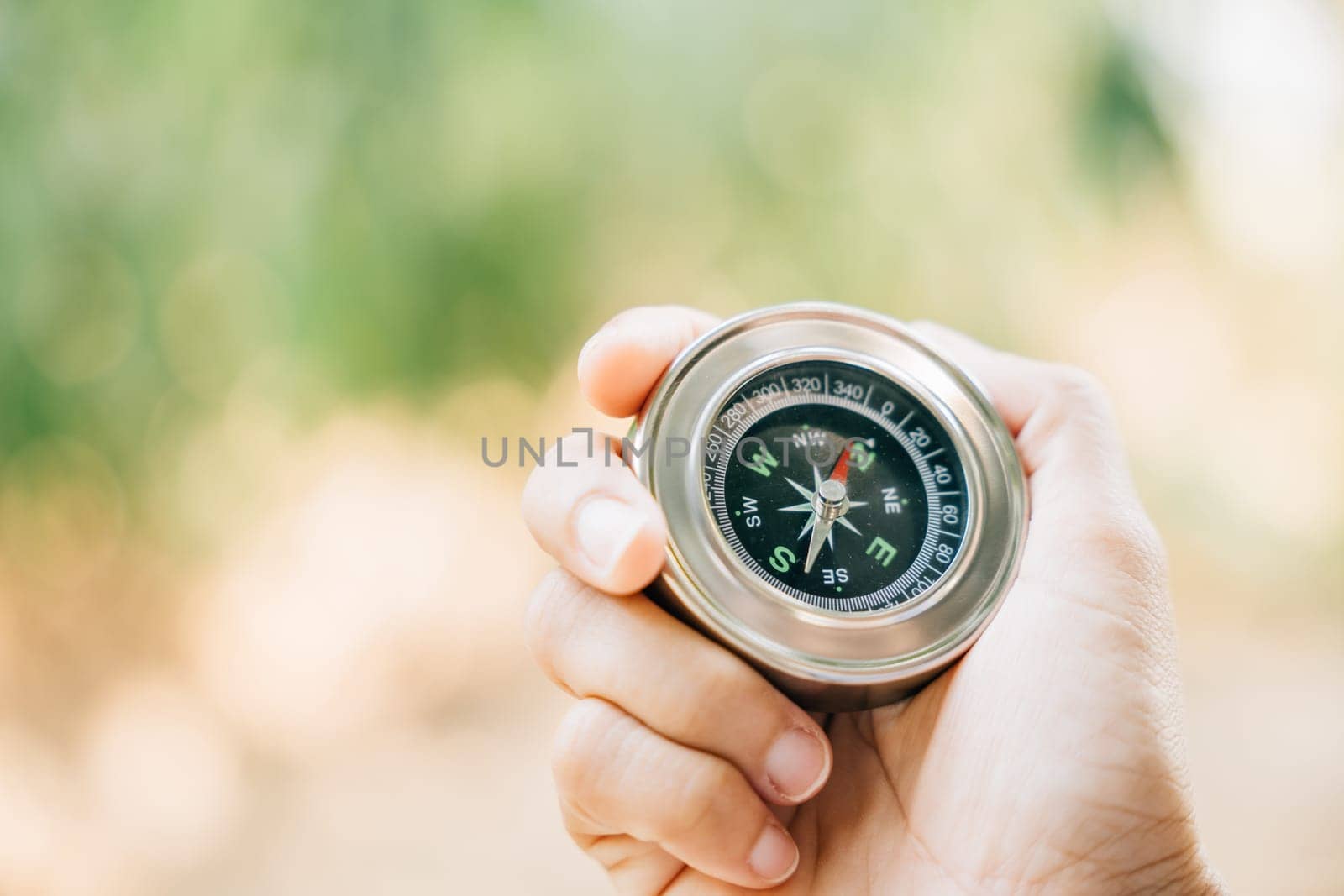 Hiker searches for direction in the forest holding a compass to overcome confusion. The compass in the hand signifies exploration and finding one way in the wilderness.