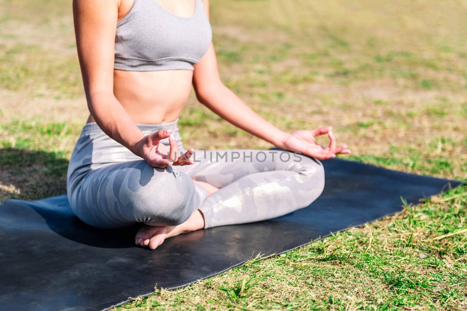 detail of the crossed legs of a woman doing meditation sitting on a yoga mat, concept of mental relaxation and healthy lifestyle