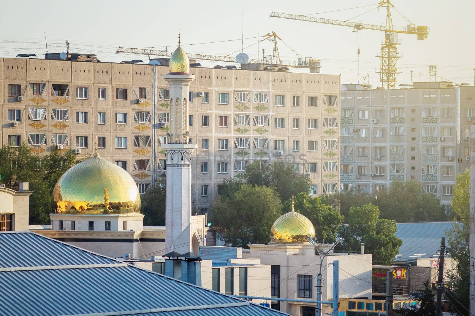 A mosque in an urban area among dense buildings of residential high-rise buildings. Almaty, Kazakhstan - September 19, 2023