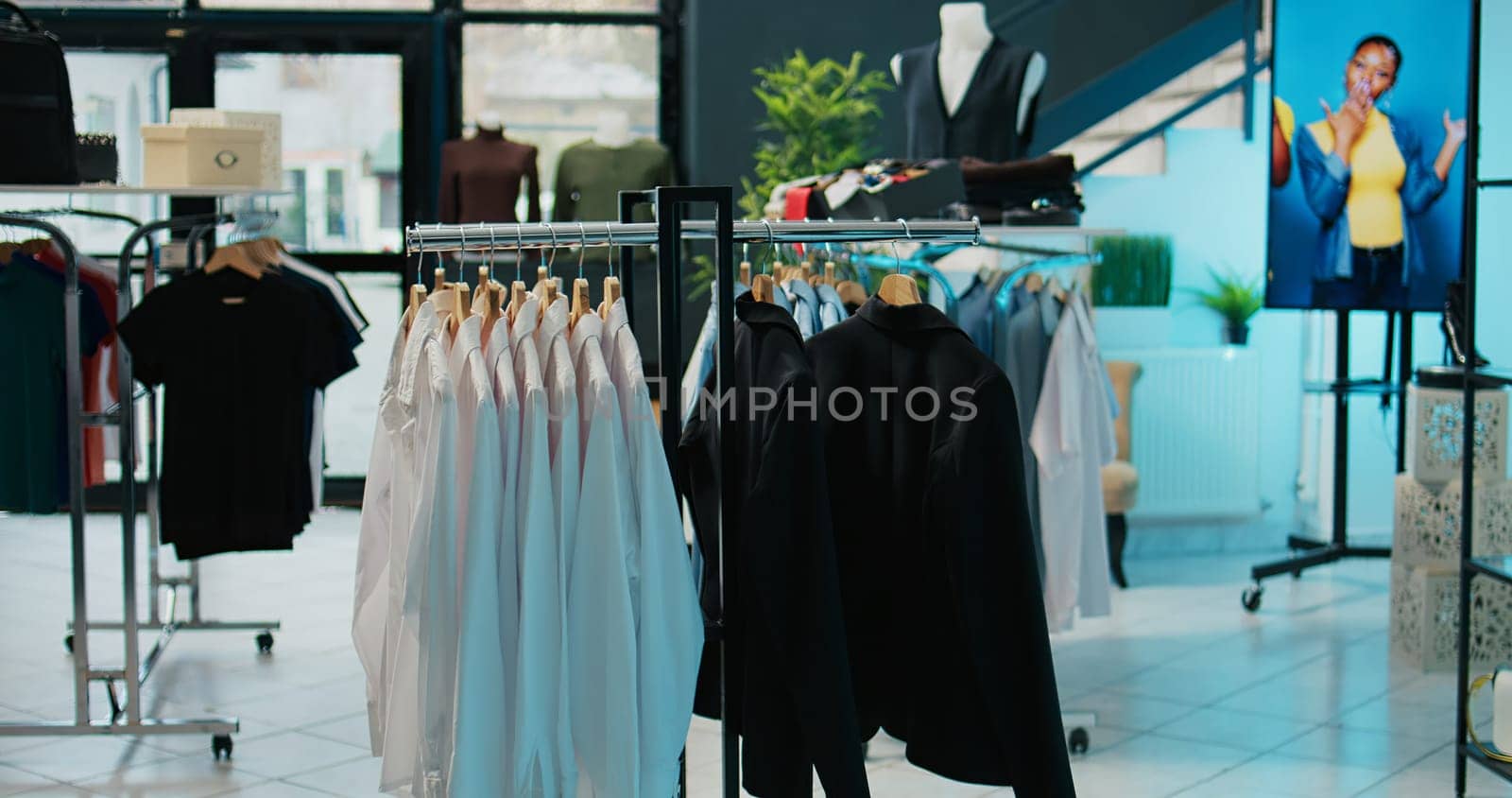 Empty trendy clothing store selling fashionable items and shoes, filled with new casual or formal merchandise. Shopping center boutique having fashion collection on racks, bags on display. Camera B.