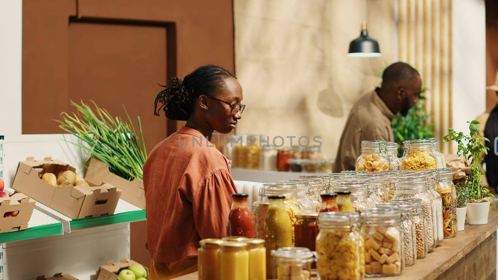 African american client examines bio homemade bulk products, looking to buy natural ethically sourced food alternatives for healthy nutrition. Woman shopping for goods at zero waste store. Camera 1.