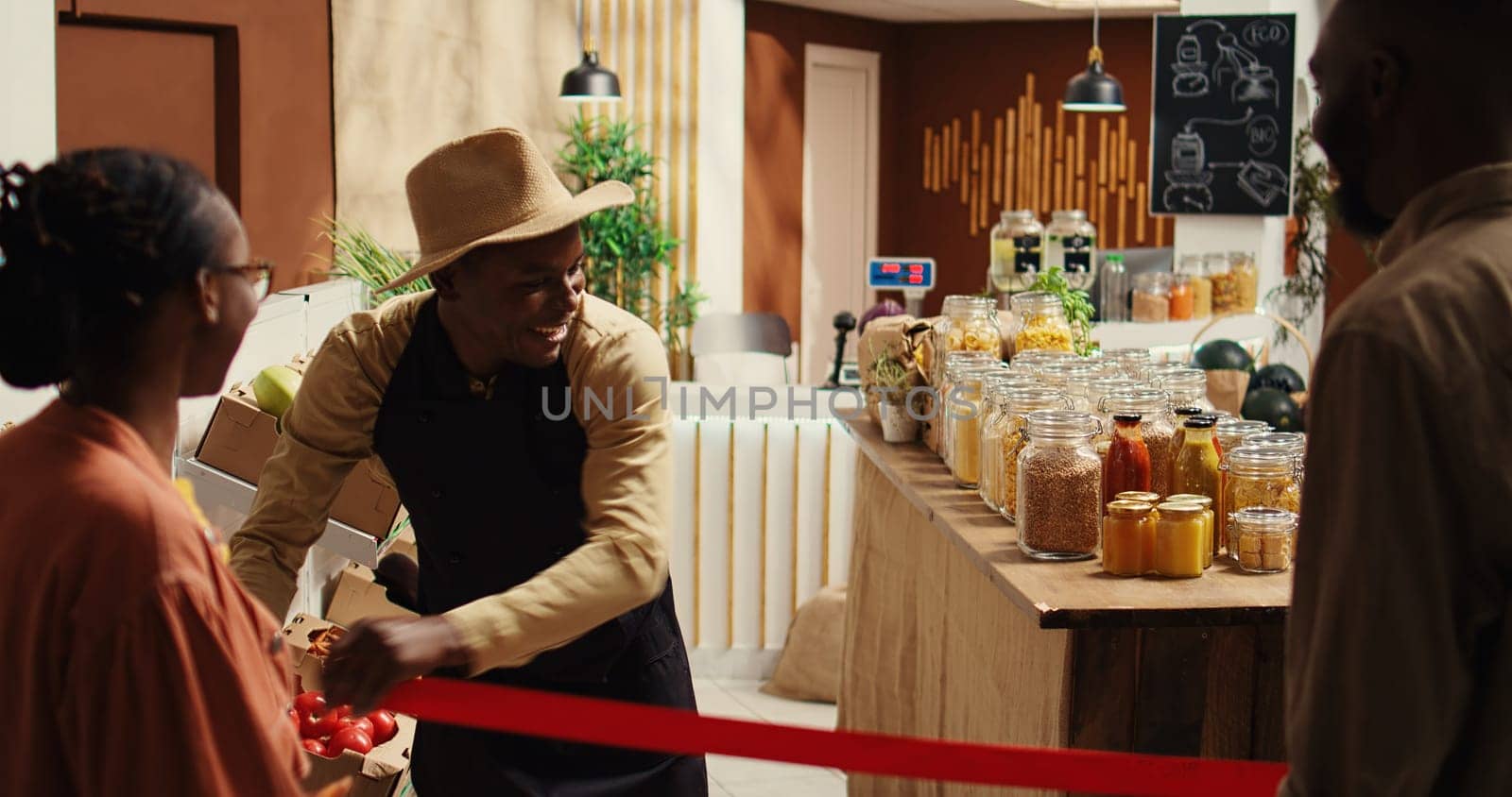 Local merchant opening grocery store doors and welcoming clients, greeting people with new organic homegrown fruits and vegetables. African american vendor selling eco friendly food items. Camera 2.