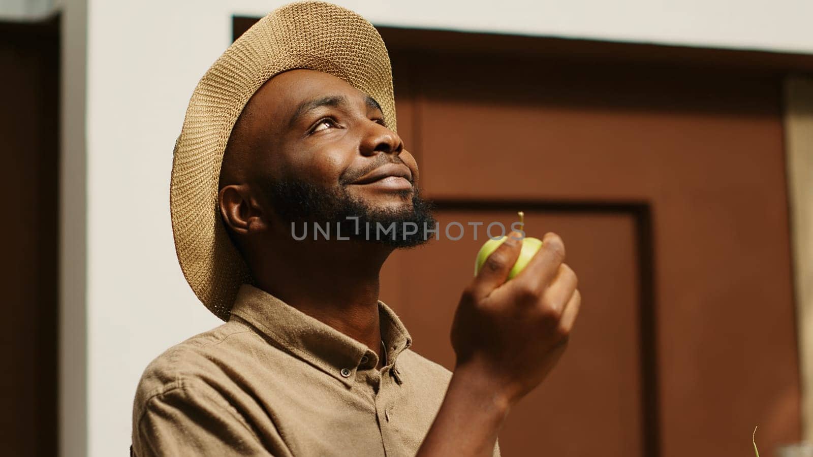 African american man smelling locally grown apples at supermarket by DCStudio