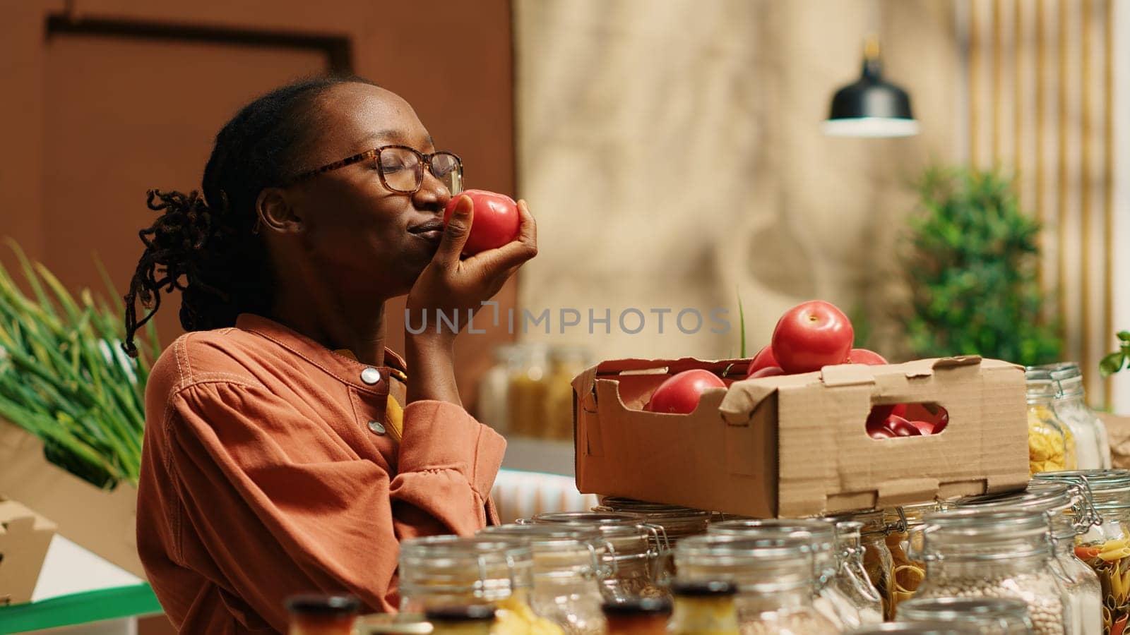 Vegan woman smelling fresh bio tomatoes from market crates, enjoying eco friendly natural aroma of locally grown produce. Regular customer choosing colorful additives free food items. Camera 1.