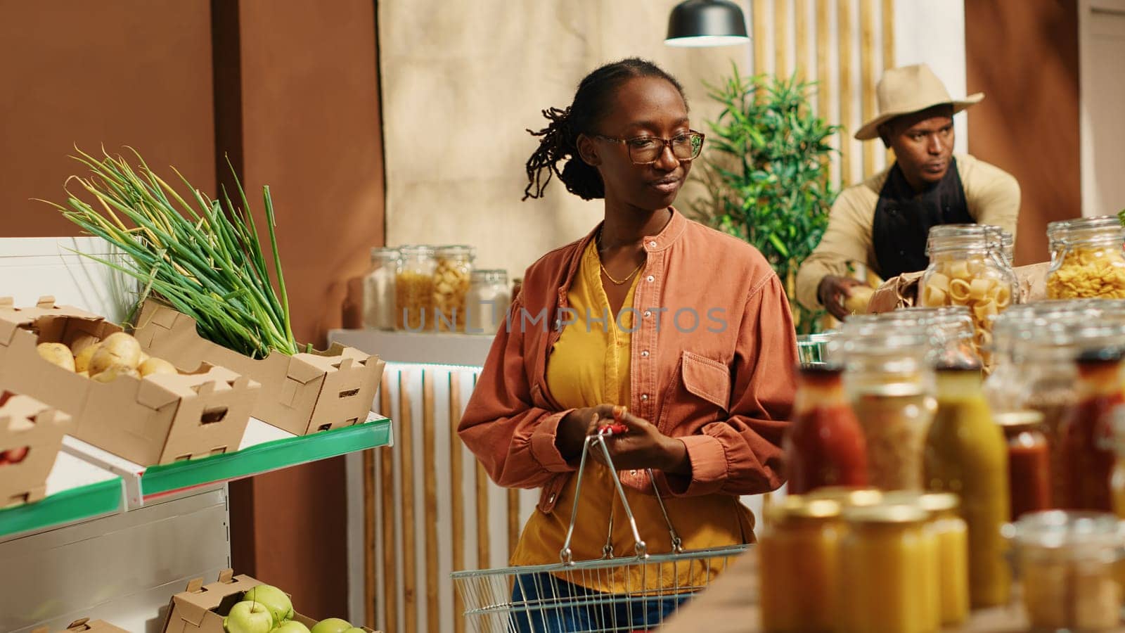 Regular customer searching for eco friendly food alternatives, looking at homemade ethically sourced bulk items at local supermarket. African american vegan woman going grocery shopping. Camera 1.
