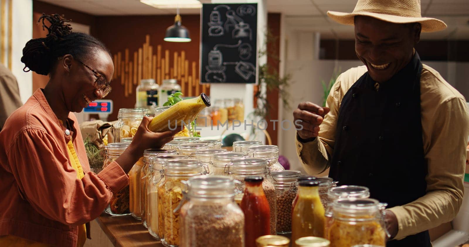 Farmer with apron recommending new homemade sauce for woman by DCStudio