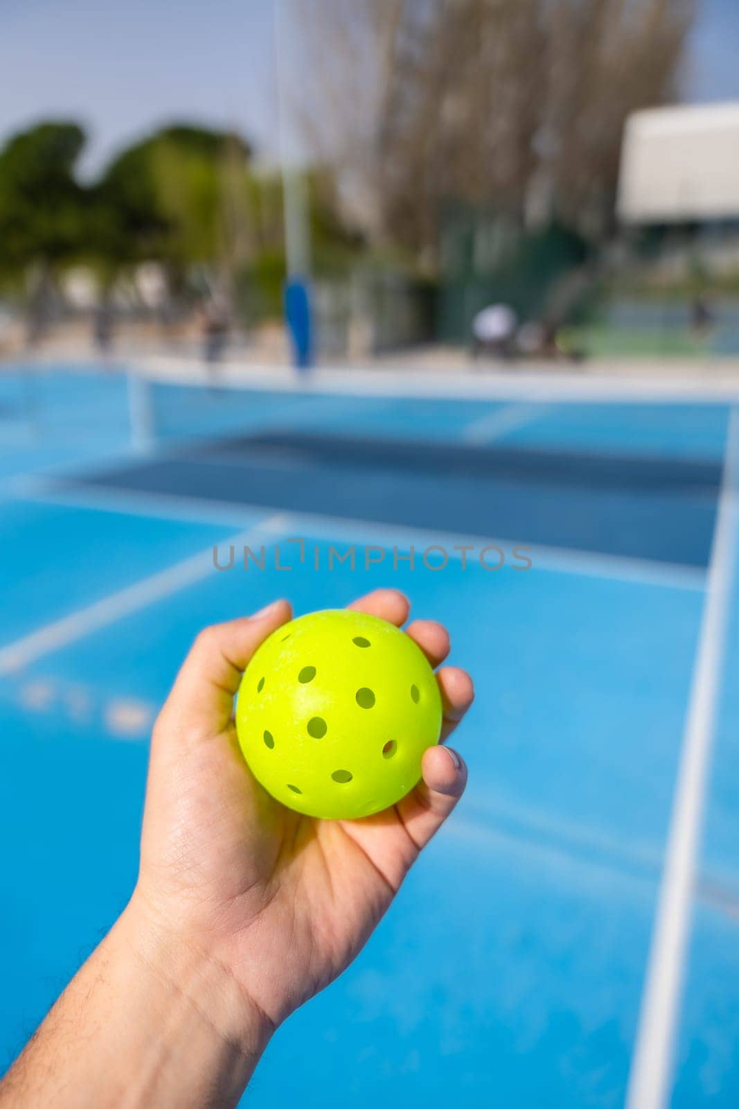 Close-up of a man holding yellow pickleball ball by Huizi