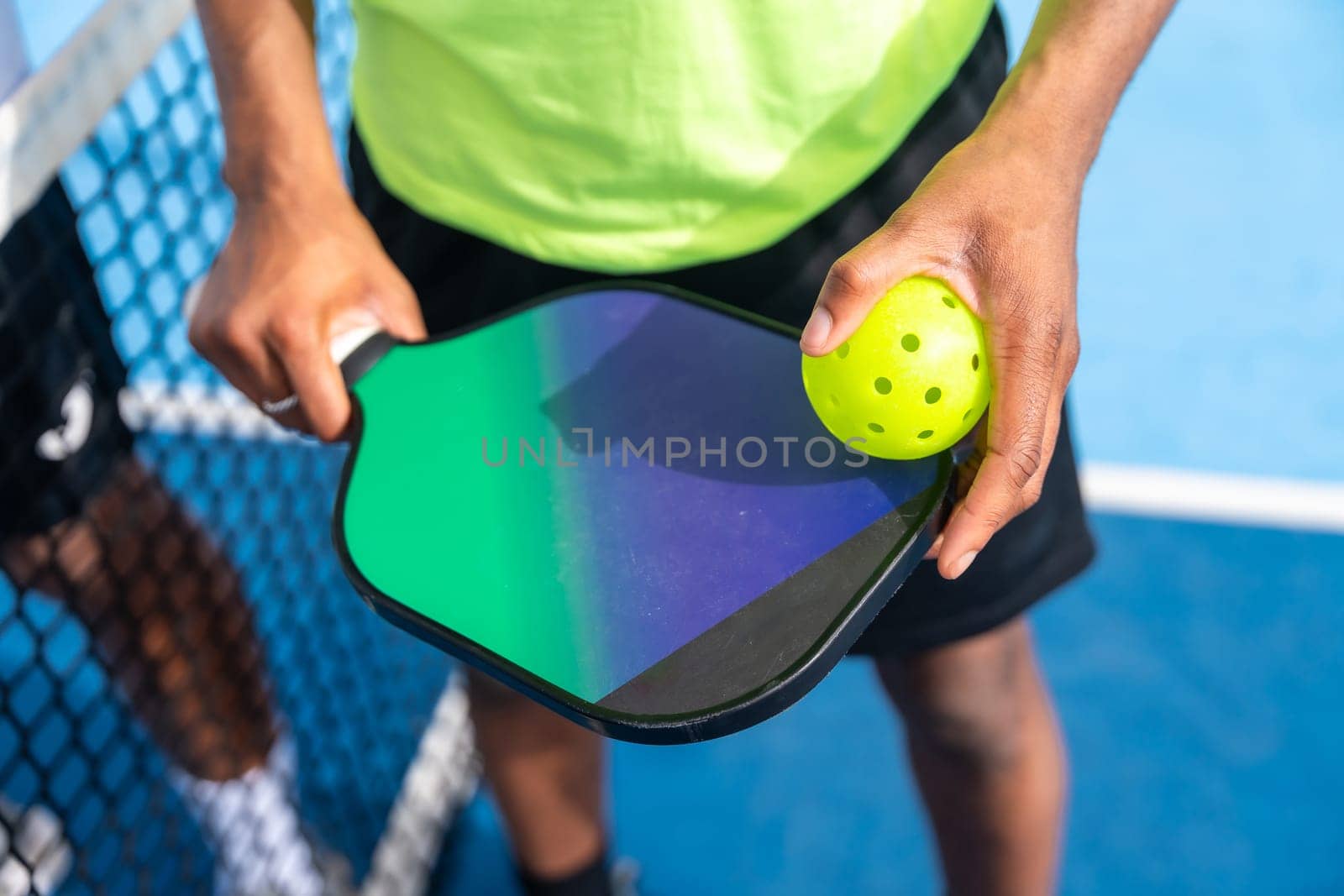 Top view close-up of man holding racket and pickleball ball by Huizi