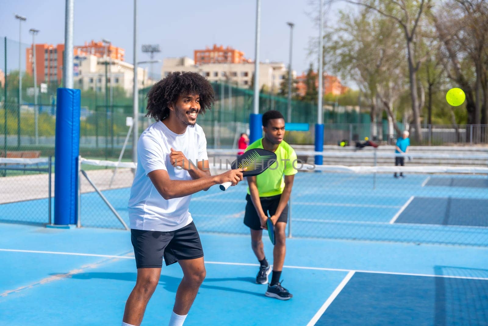 Friends enjoying playing pickleball together in an outdoor court by Huizi