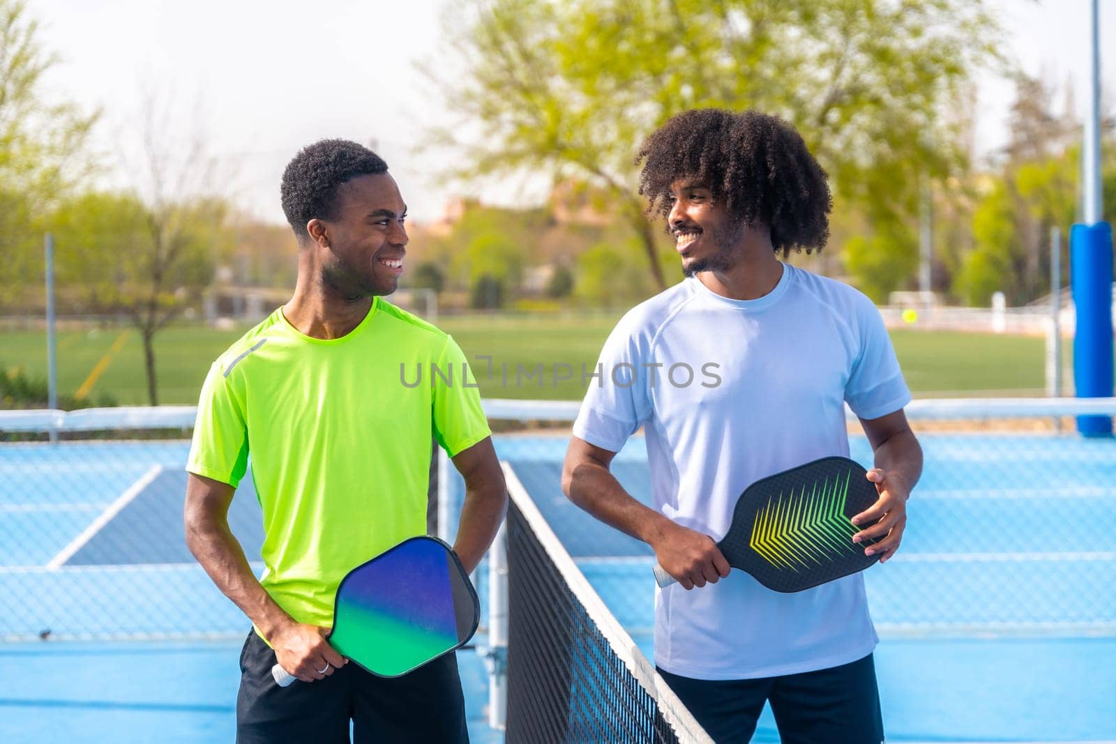 Friends smiling standing in a pickleball court by Huizi