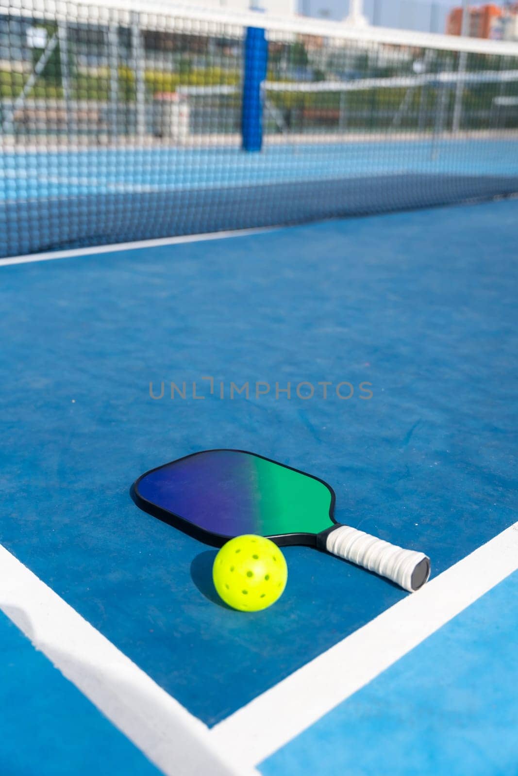 Racket and yellow pickleball ball on a court by Huizi