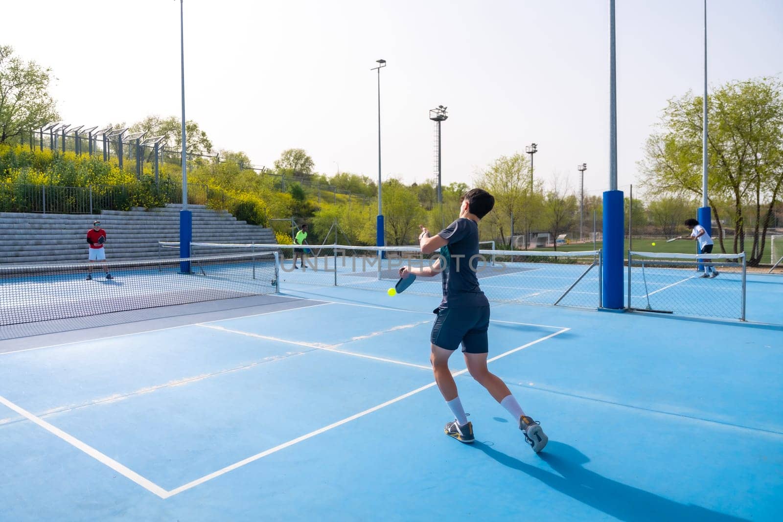 Men playing pickleball in an outdoor court by Huizi