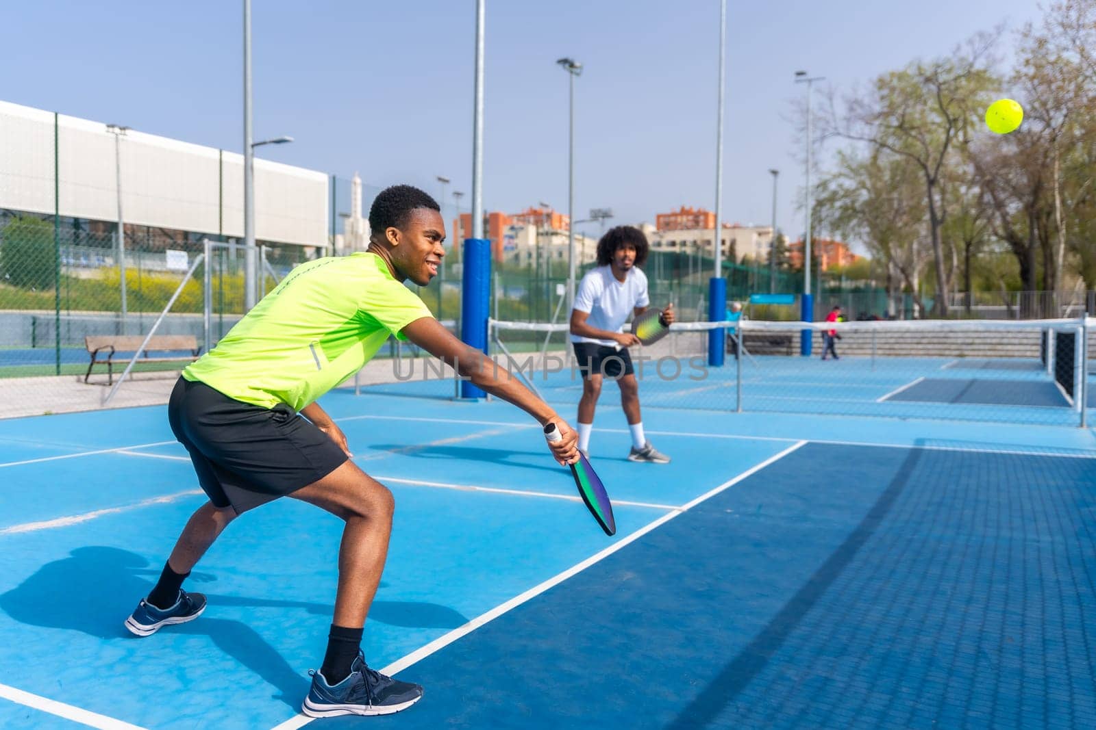 Friends having fun during pickleball match outdoors by Huizi