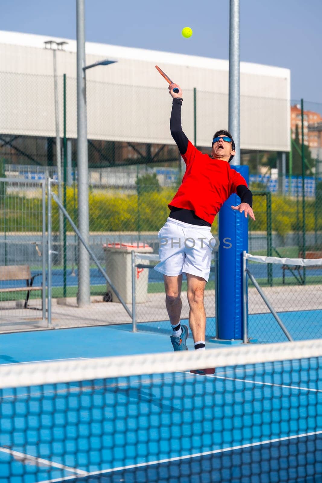 Man jumping to reach the ball in a pickleball court by Huizi