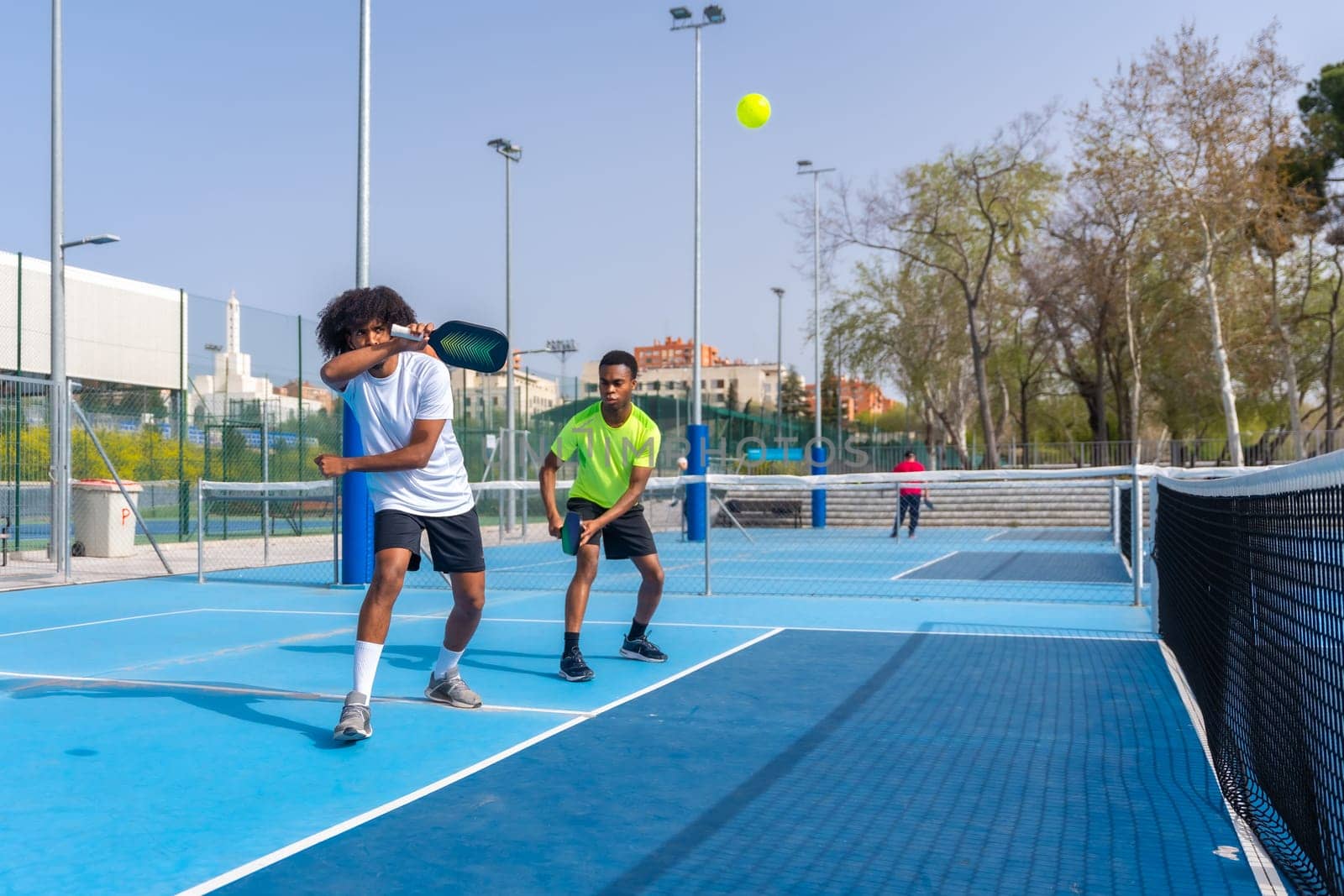 African sportive friends playing pickleball together outdoors by Huizi