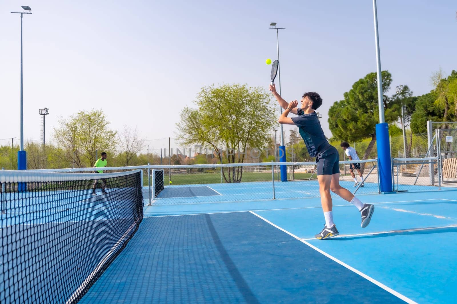 Man jumping while playing pickleball in an outdoor facility by Huizi