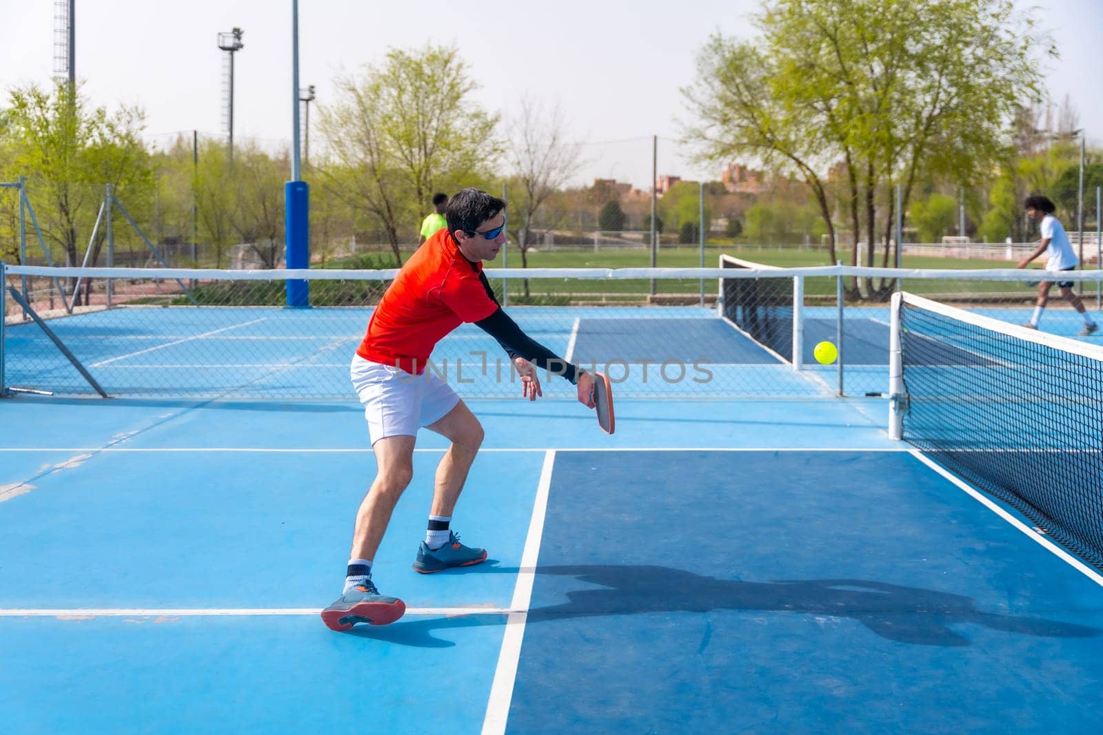 Man in sportive clothes playing pickleball outdoors by Huizi