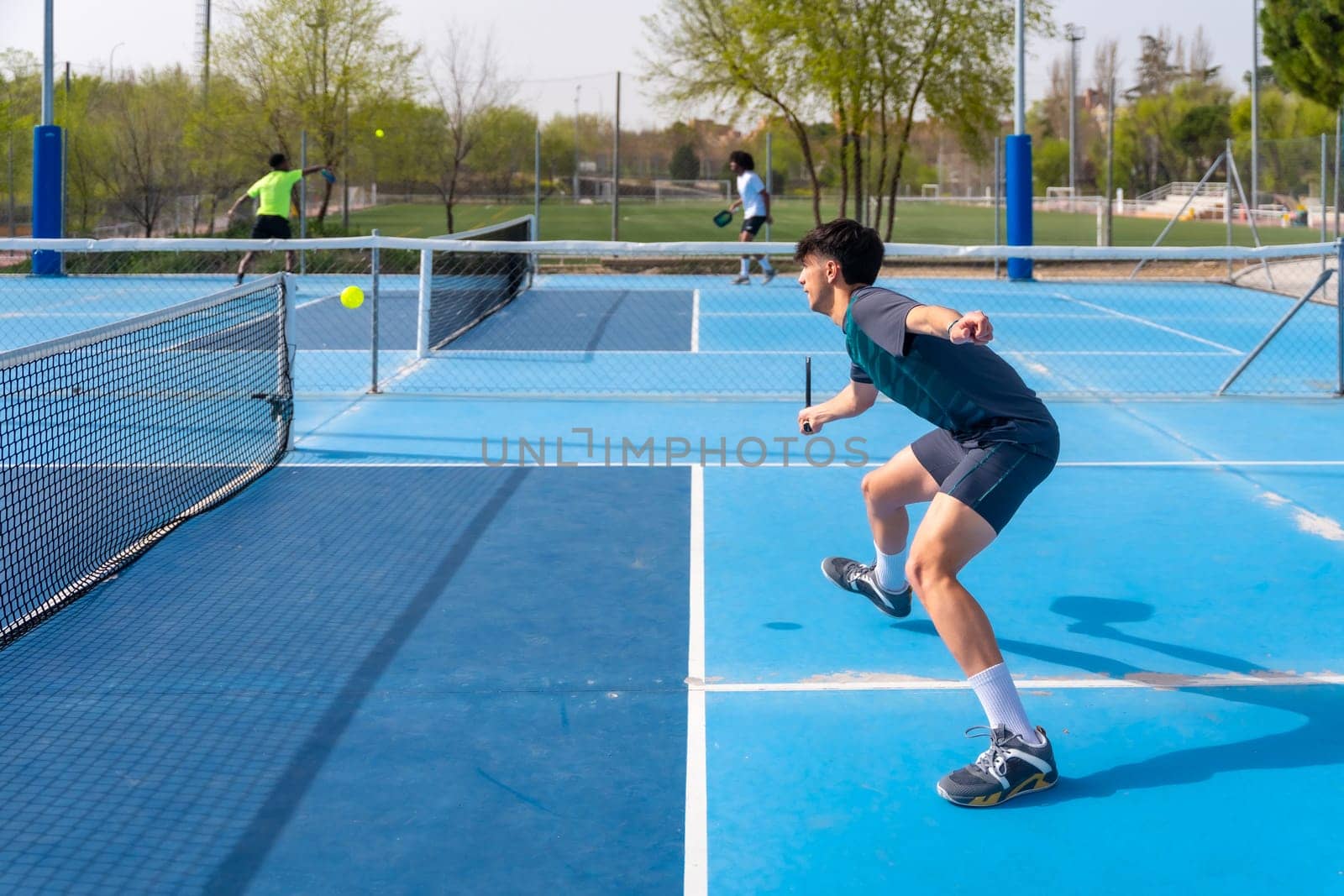 Sportive young man playing pickleball under the sun by Huizi