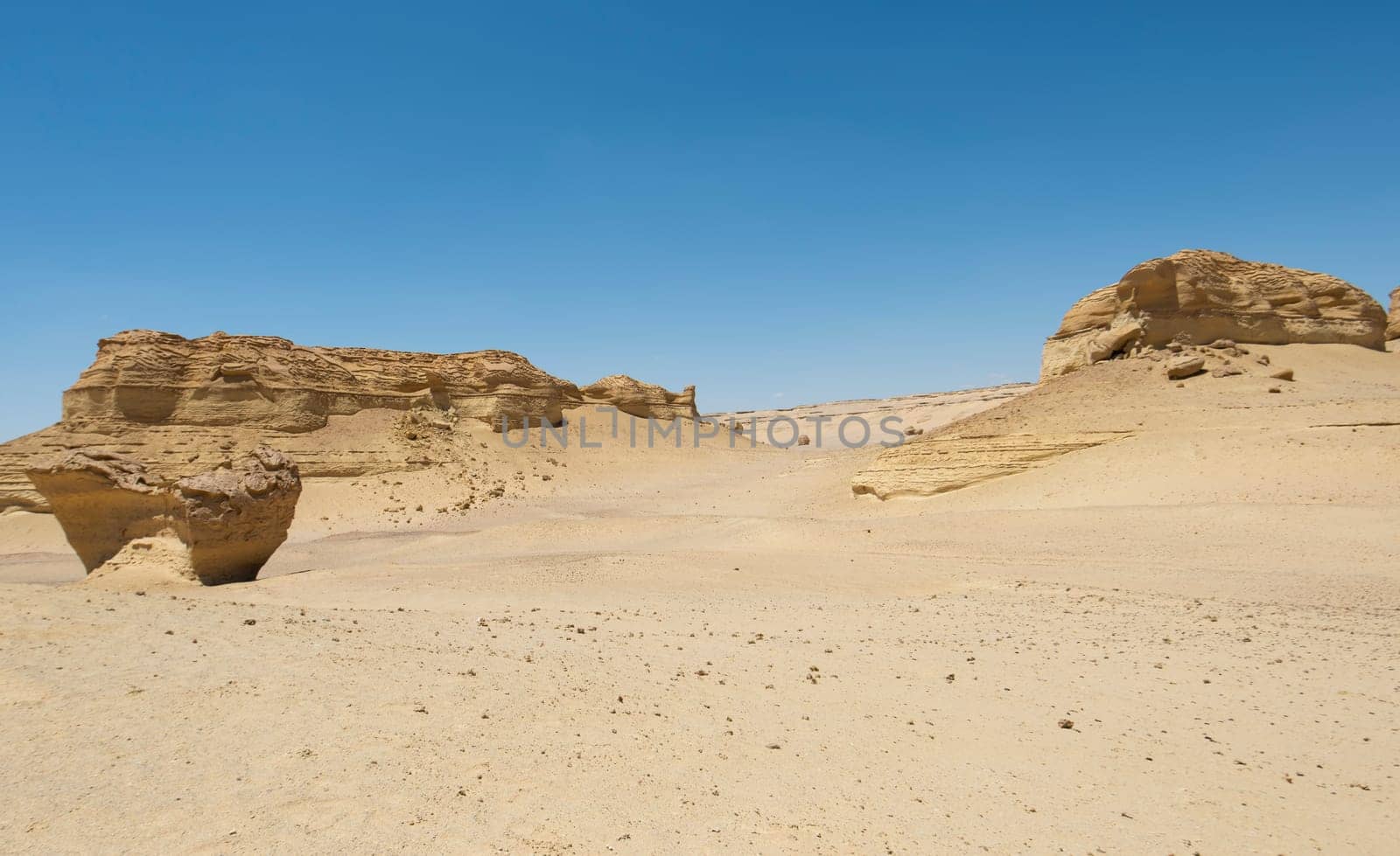 Barren desert landscape in hot climate with mountain rock formation by paulvinten