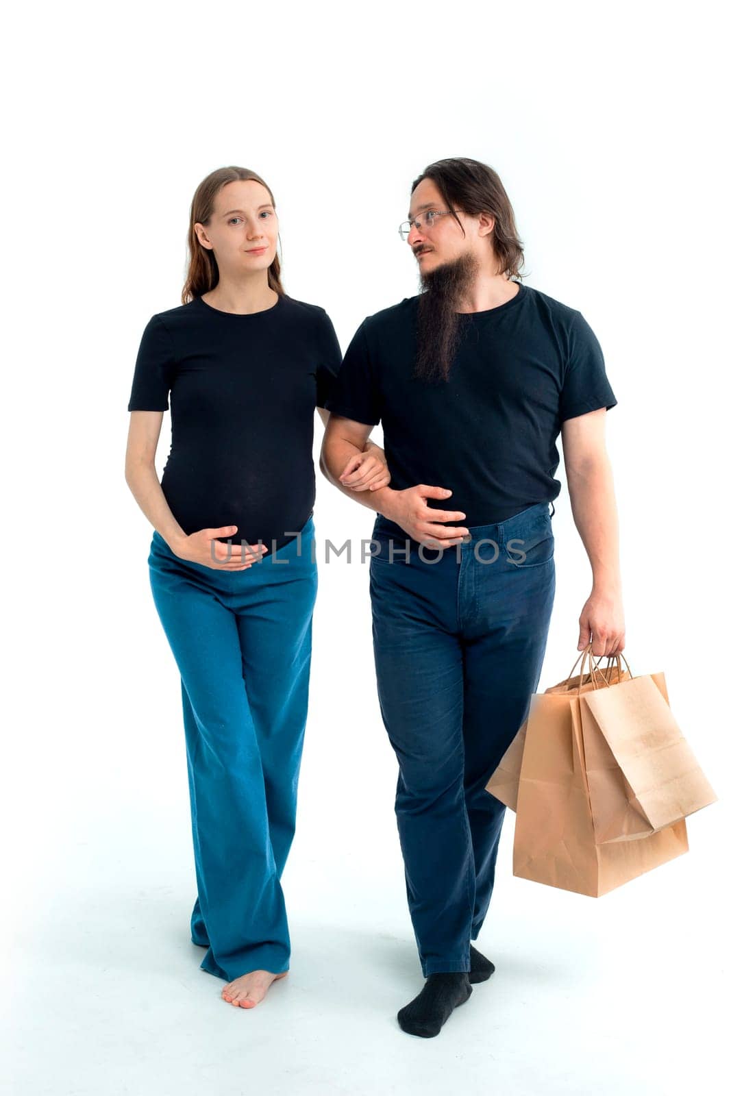 Portrait happy young pregnant woman and her husband with shopping bags and touching her big belly isolated on white background. Pregnancy shopping concept happy young family with shopping bags