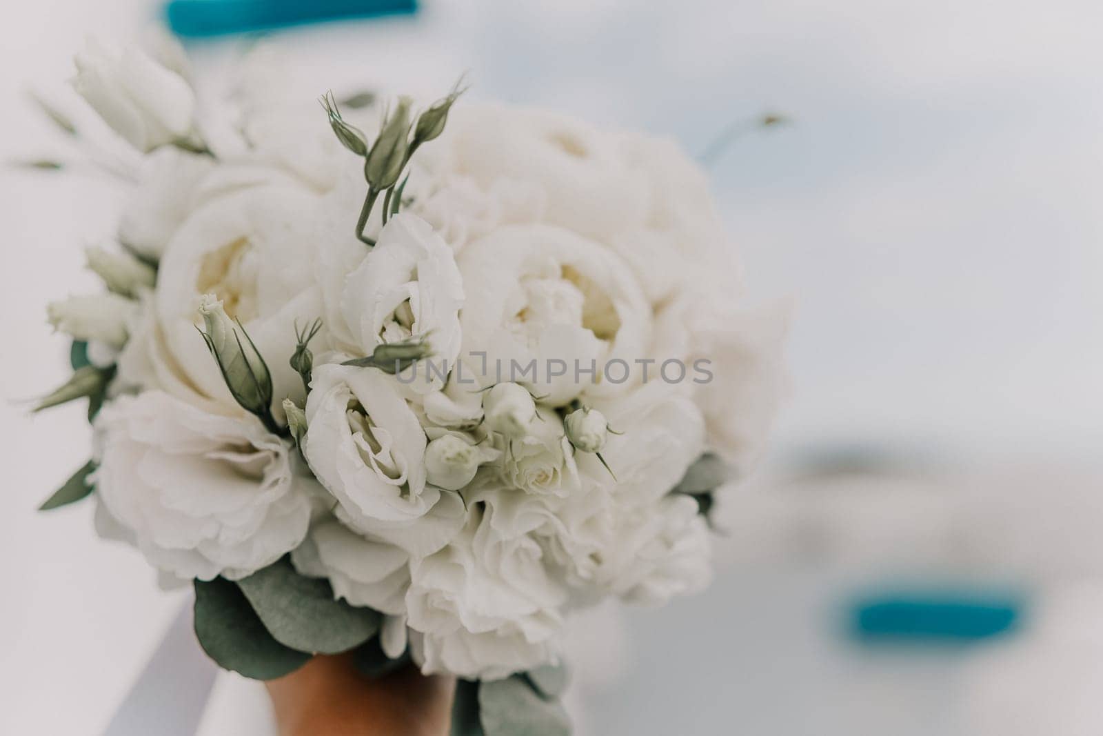 A bouquet of white flowers is being held by a person. The flowers are arranged in a way that they look like they are in a vase. The bouquet is the main focus of the image