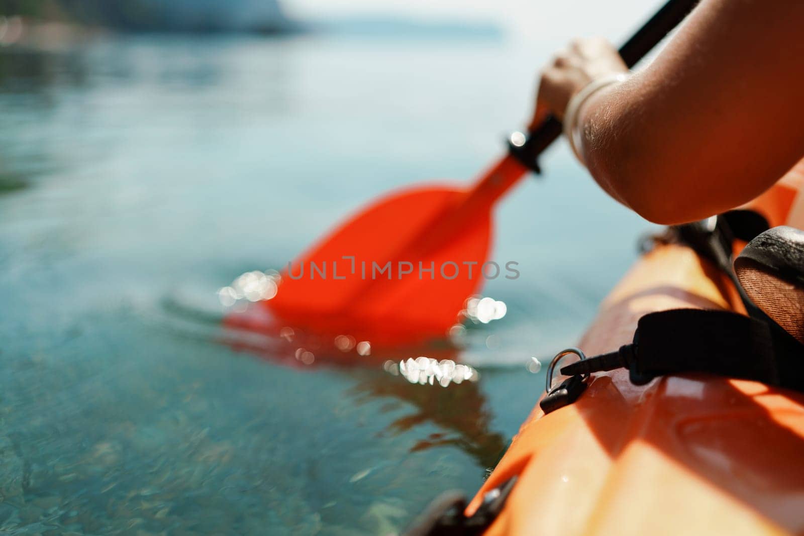 Kayak paddle sea vacation. Person paddles with orange paddle oar on kayak in sea. Leisure active lifestyle recreation activity rest tourism travel by Matiunina