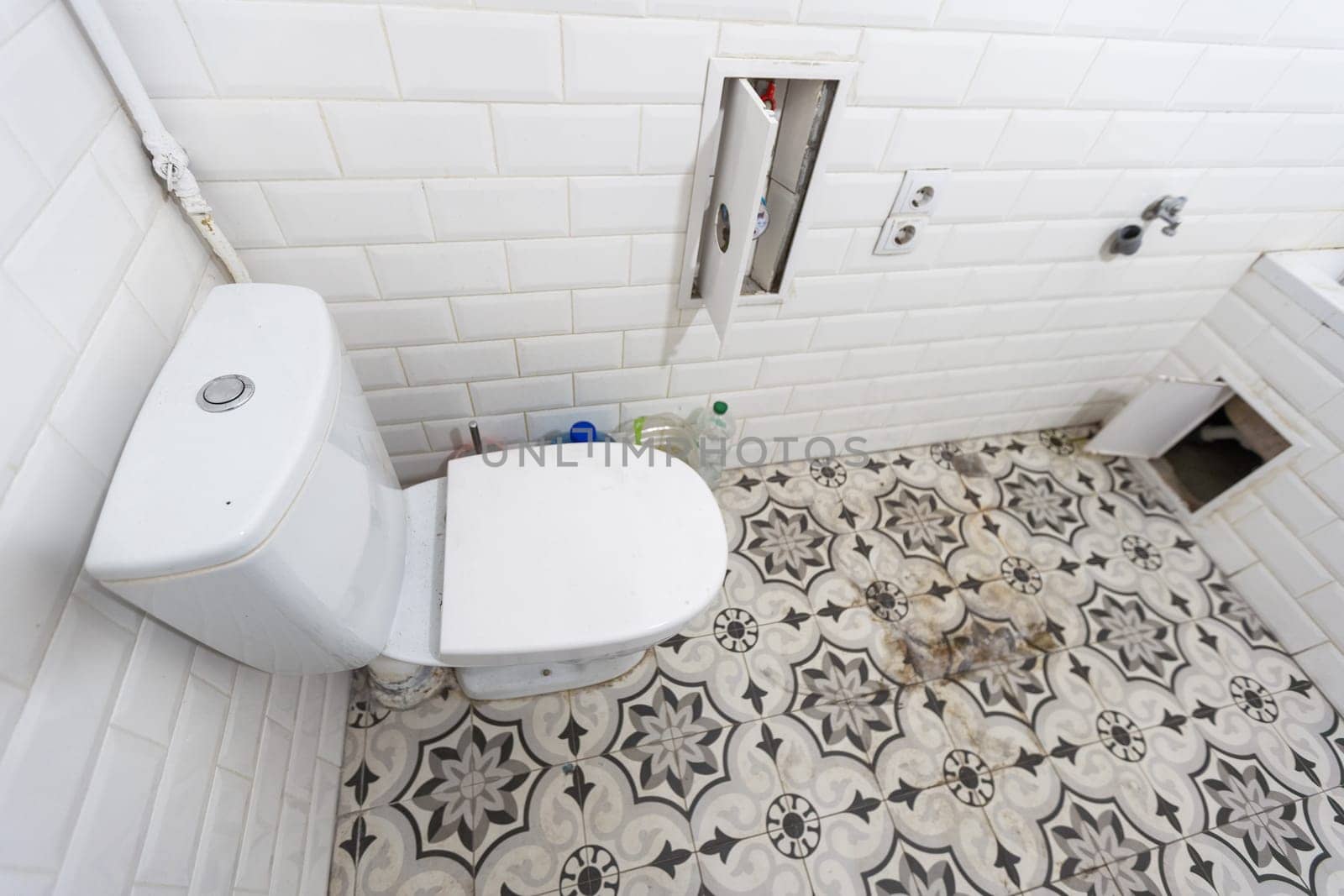 Interior of narrow restroom with wall hung toilet with white walls and checkered floor. High quality photo