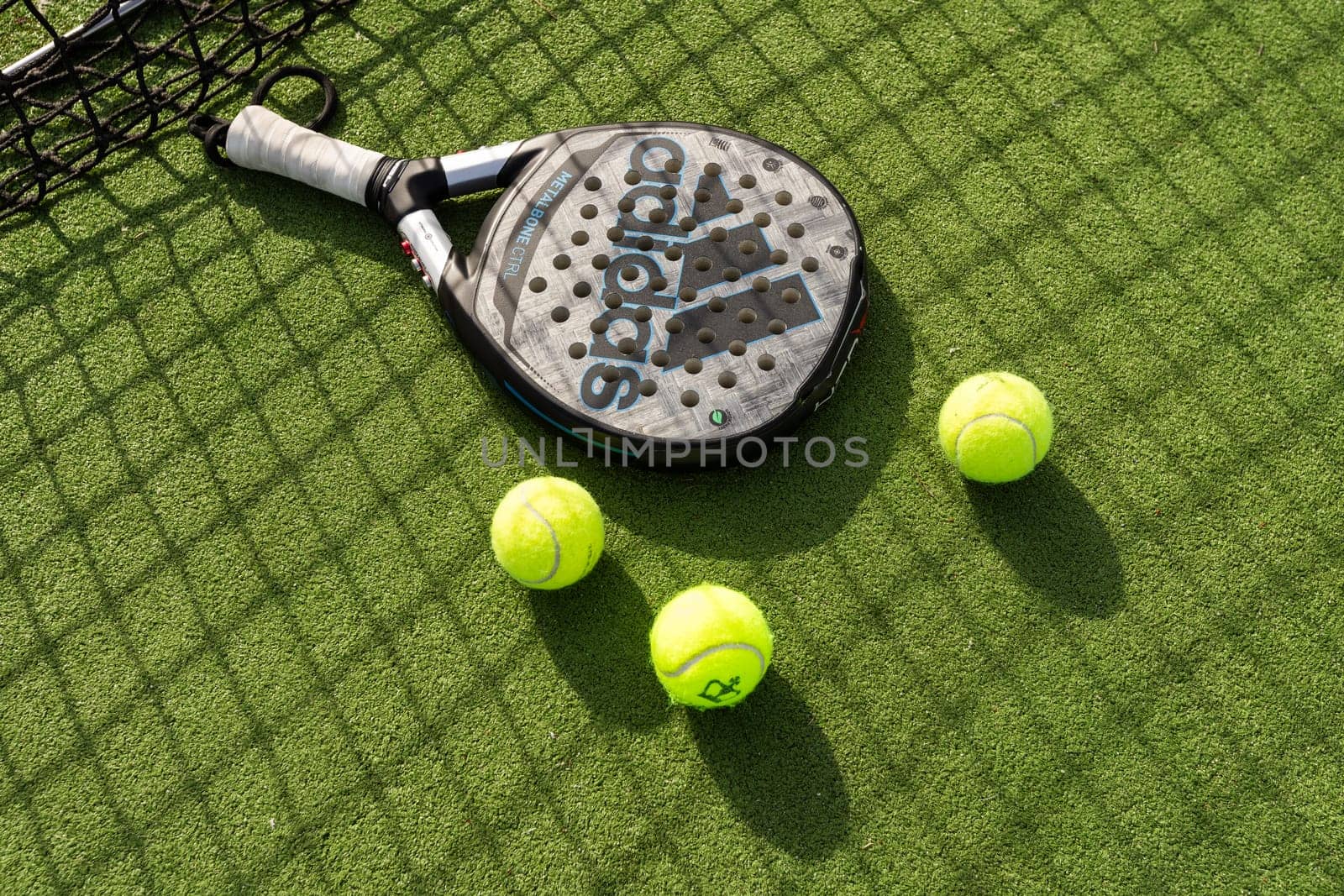 Ukraine Kyiv, 31.03.2024: Padel racket adidas and padel ball on a green court . High quality photo