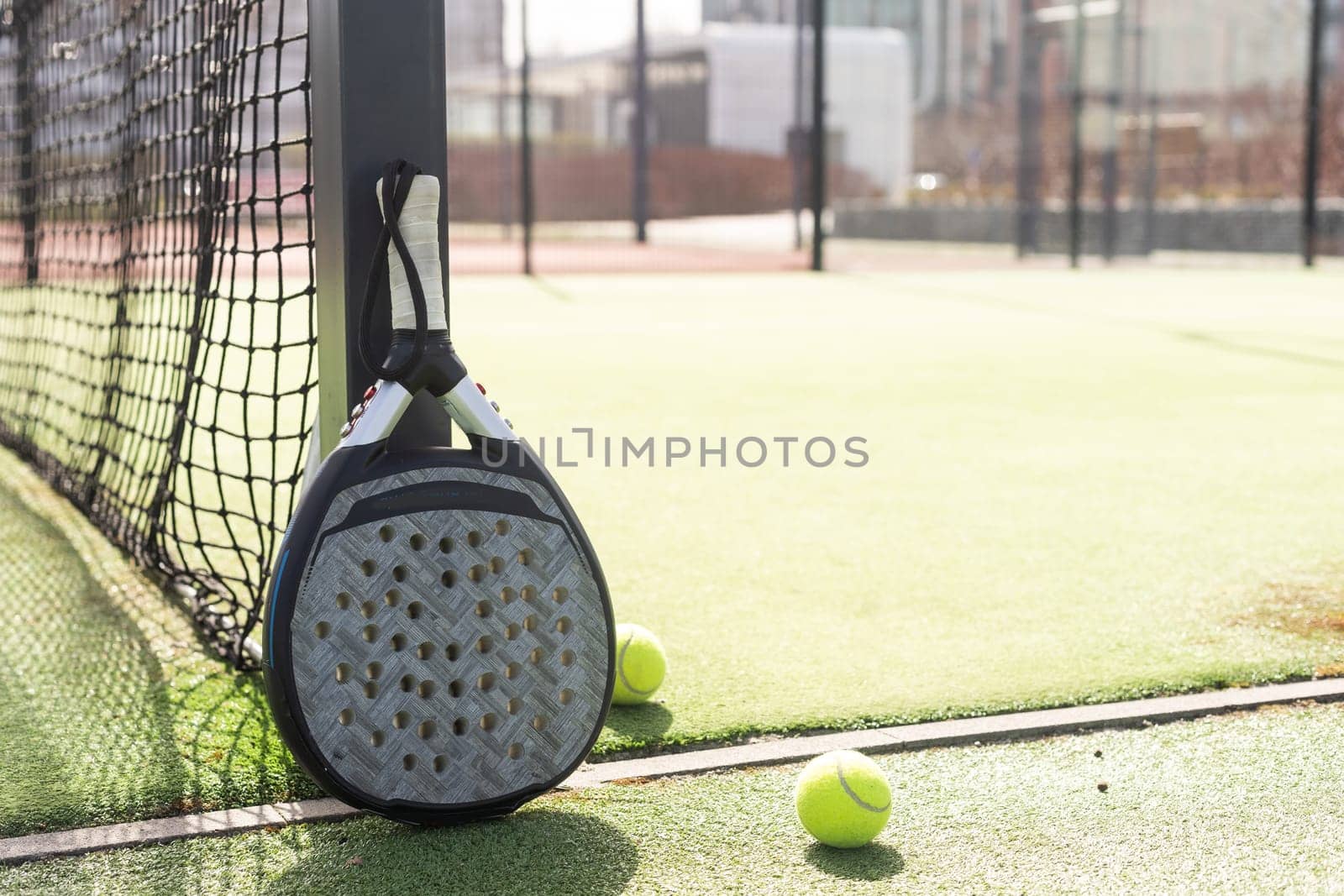 Padel racket and padel ball on a green court in the sunset. High quality photo
