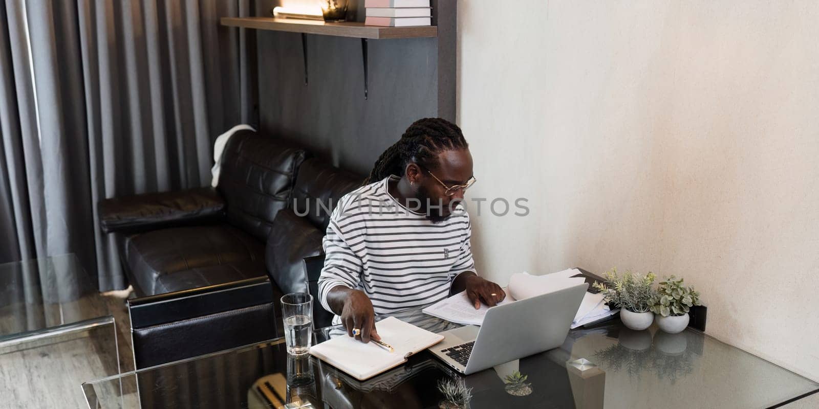 Young African American business man working with laptop and document on desk at home. work from home concept by itchaznong