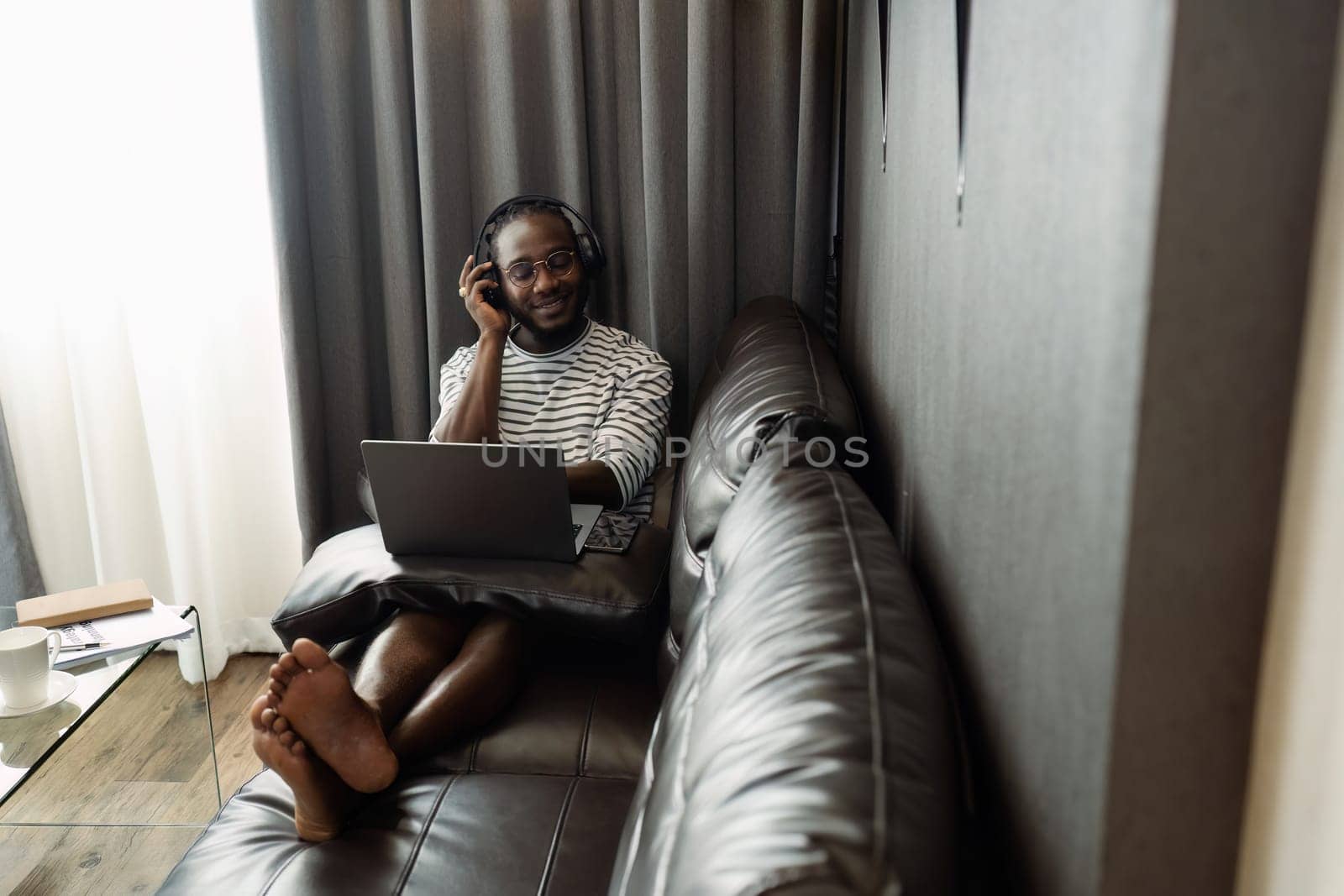 African American man relaxing on sofa and listening to music at home.